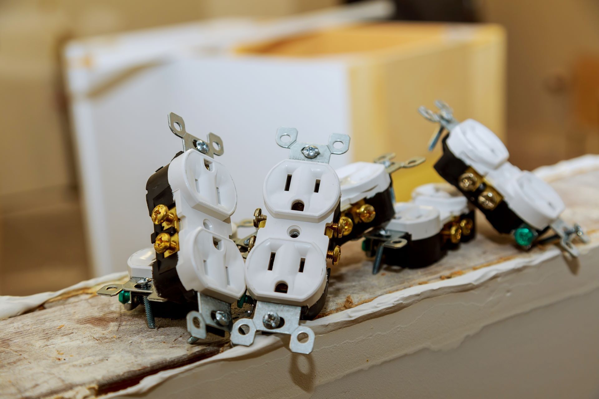 Electrical outlets sit on a wooden surface. Some have exposed wiring. White and black plastic.