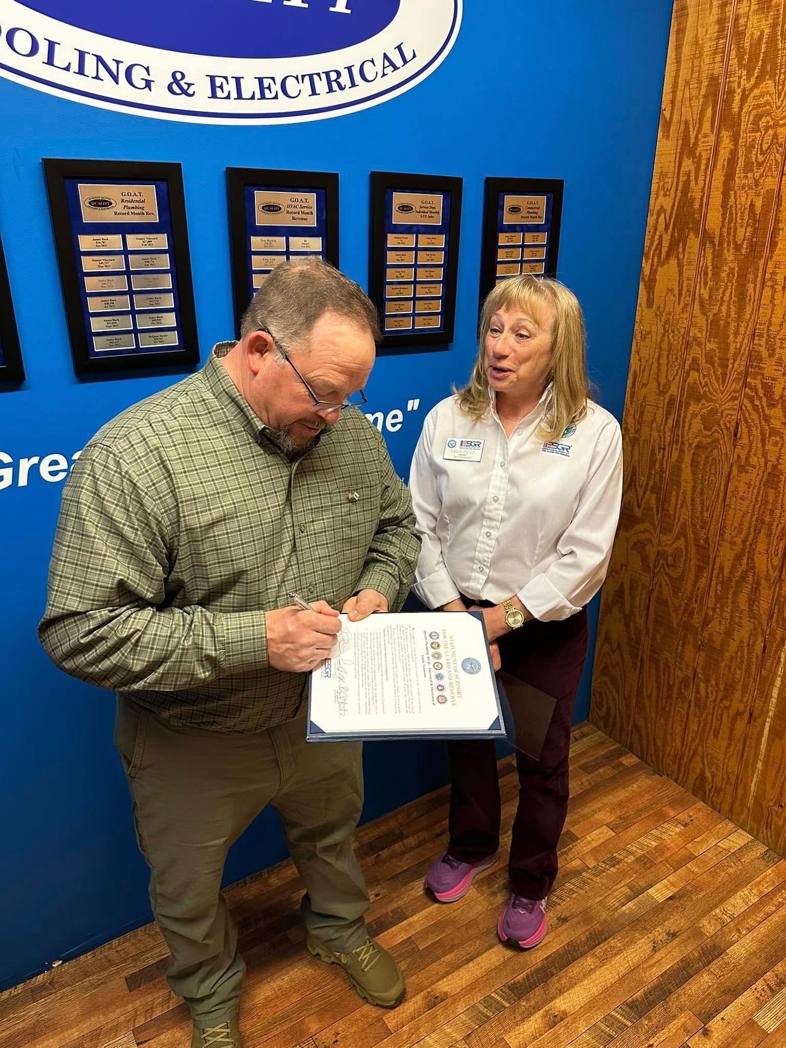 A man and a woman are standing next to each other in front of a blue wall.