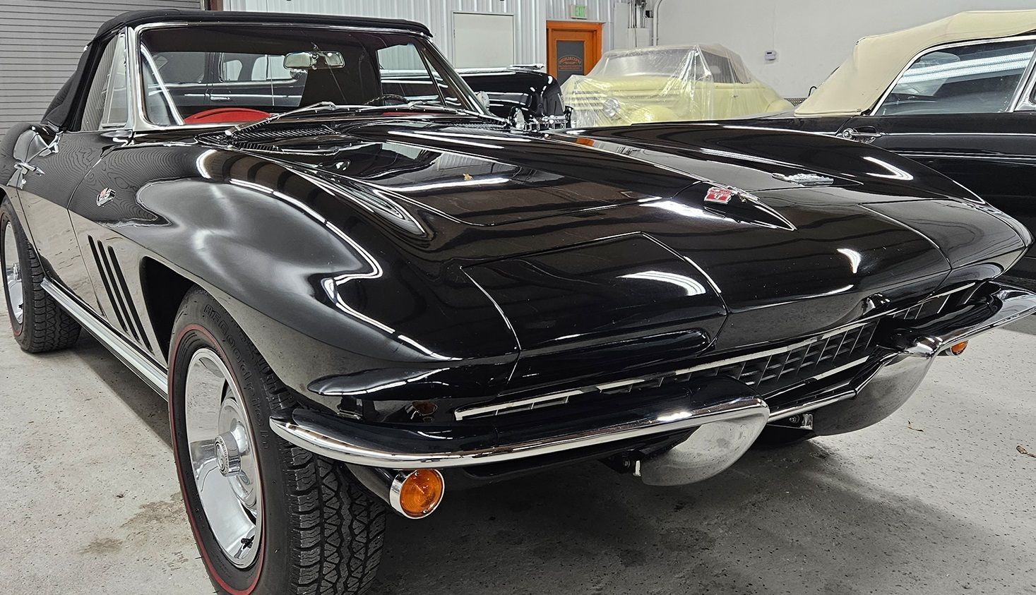 Black vintage Corvette convertible car in a garage.