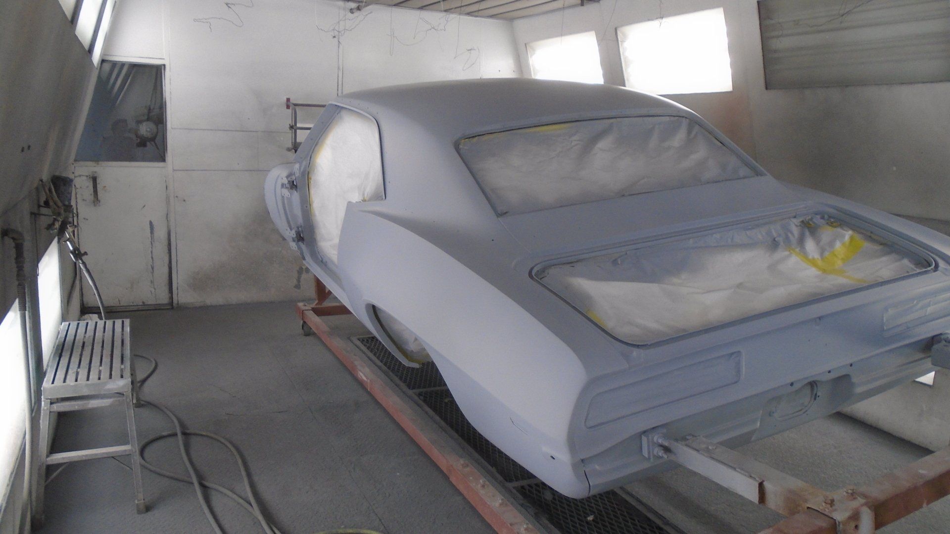Classic car in a paint booth, primed and ready for painting.