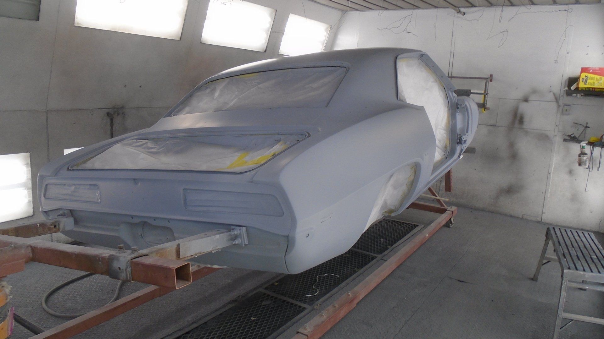 Car body in a spray booth, primed and masked for painting.