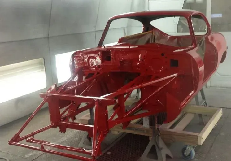 Red car chassis in a paint booth.