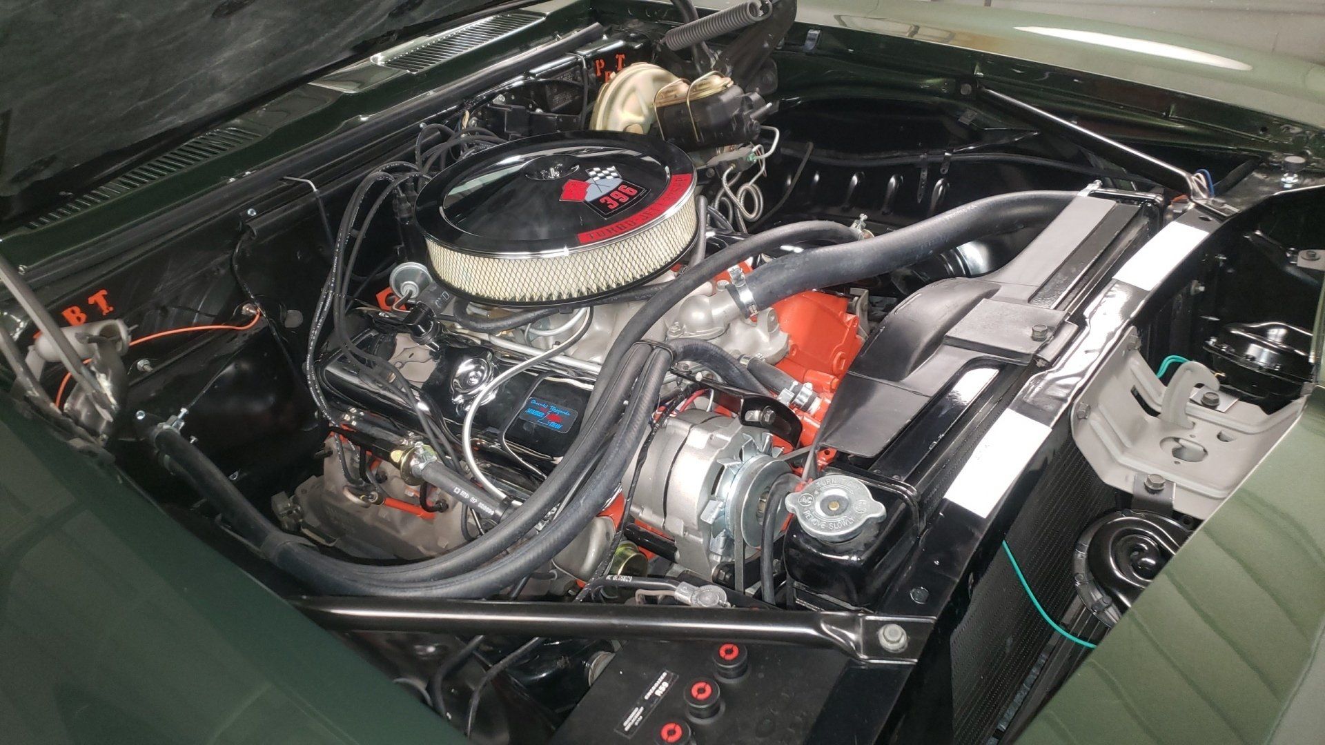 Green car engine bay with a Chevy engine and chrome details.