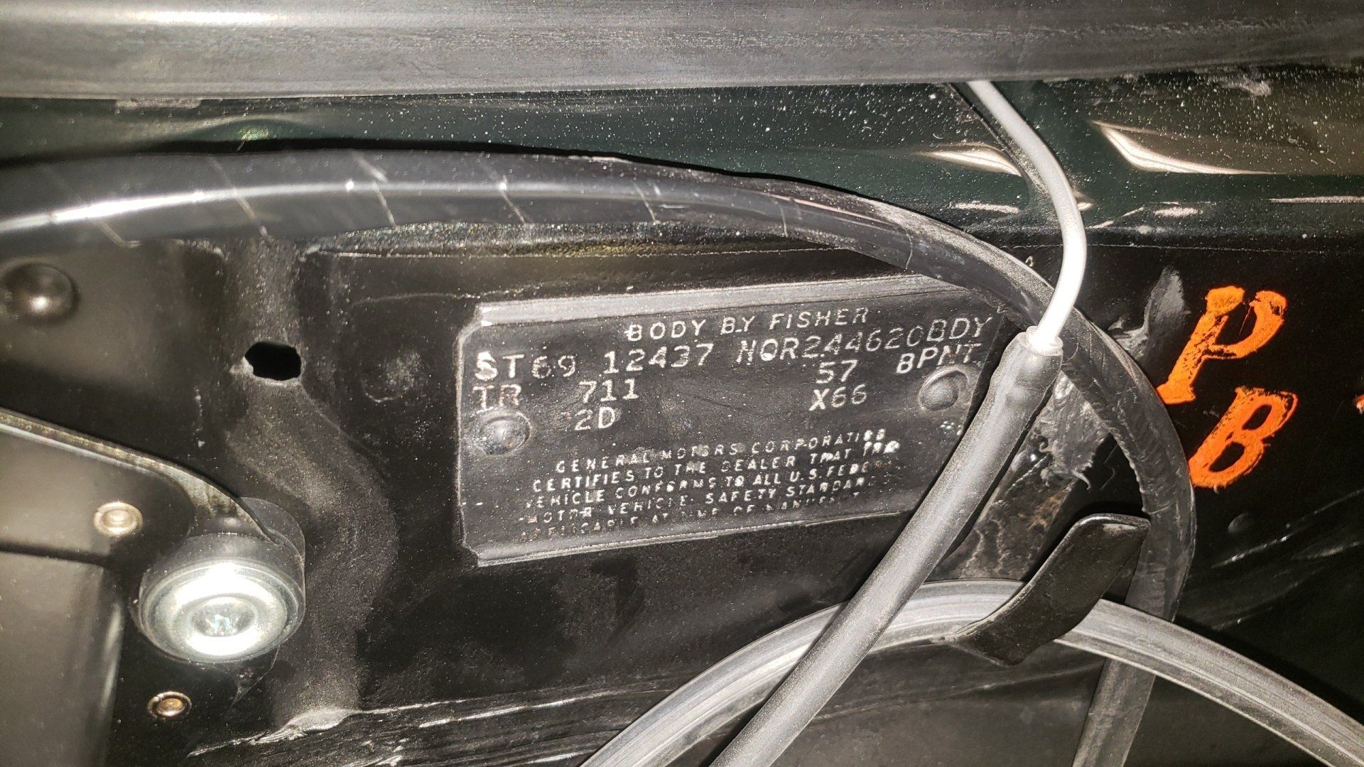 Black metal car data plate with text, wires, and screws visible.