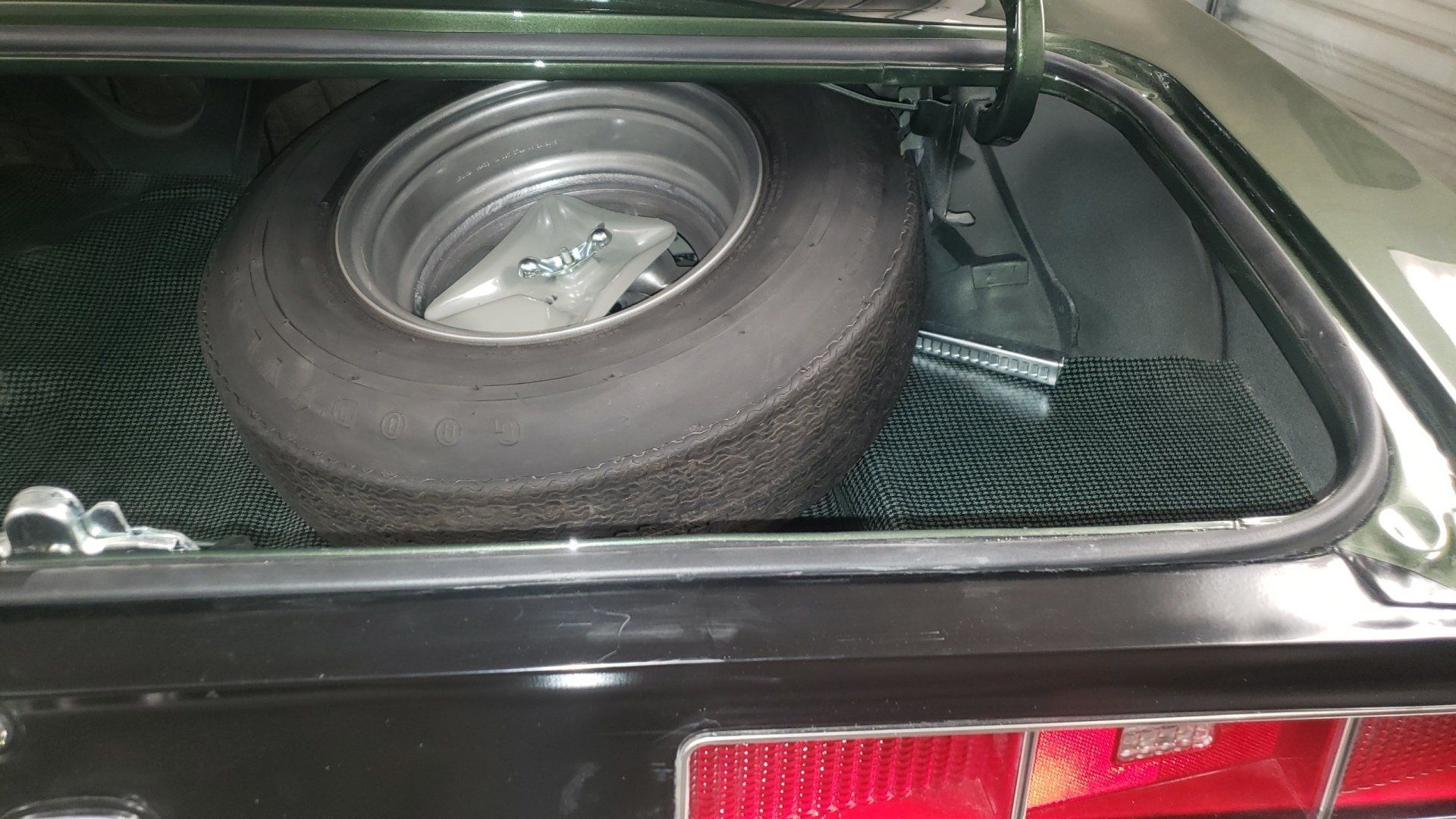 Car trunk with a spare tire. Black and green interior.