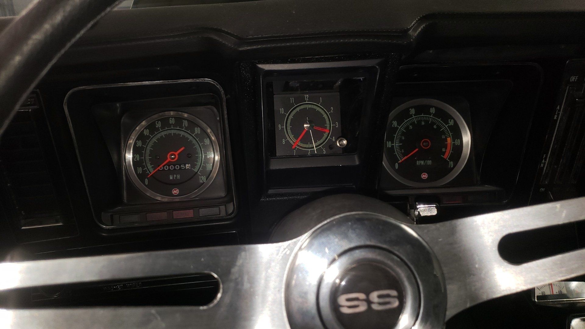 Dashboard of a classic black car with gauges and an 