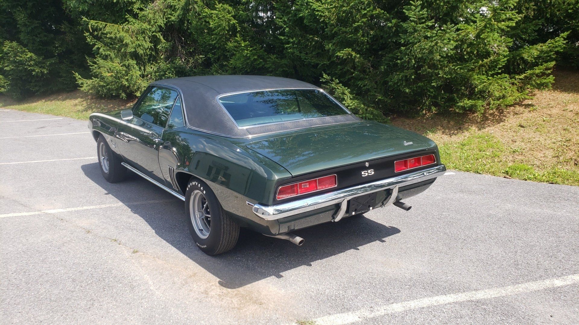 Green 1969 Chevrolet Camaro SS parked on asphalt, black vinyl top, chrome trim, and rear end details.