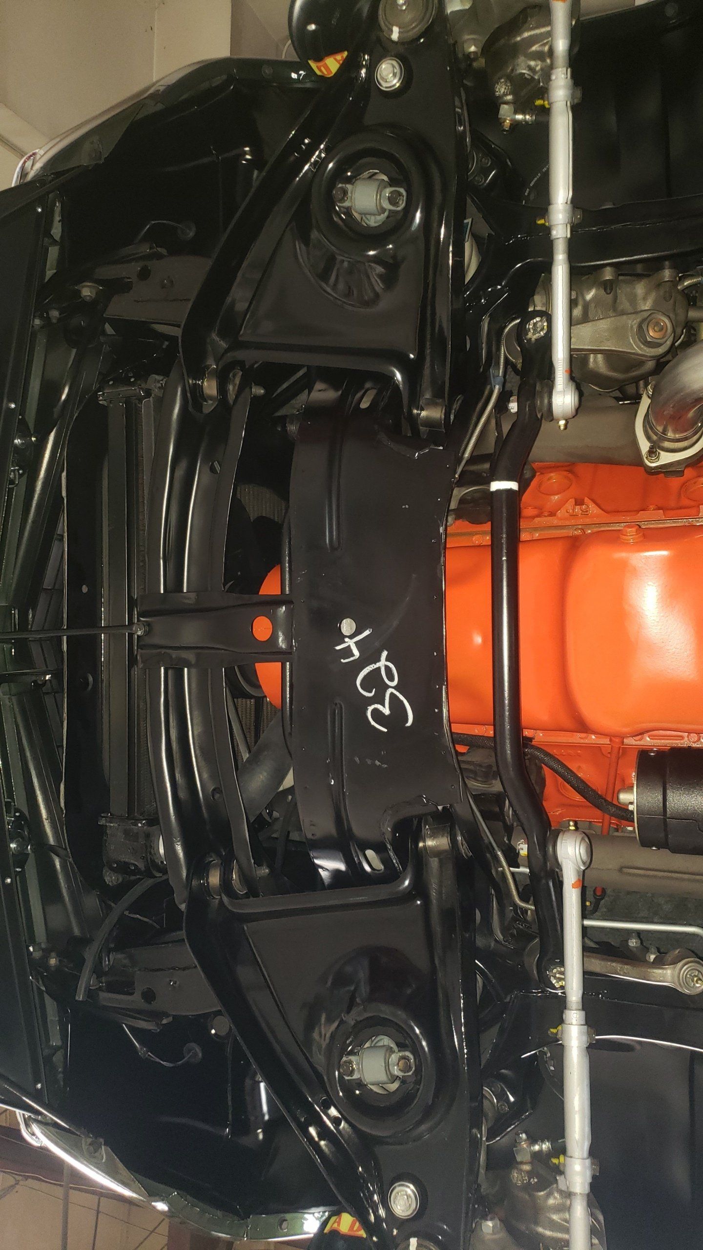 Undercarriage of a black car with an orange engine; supports and suspension visible.