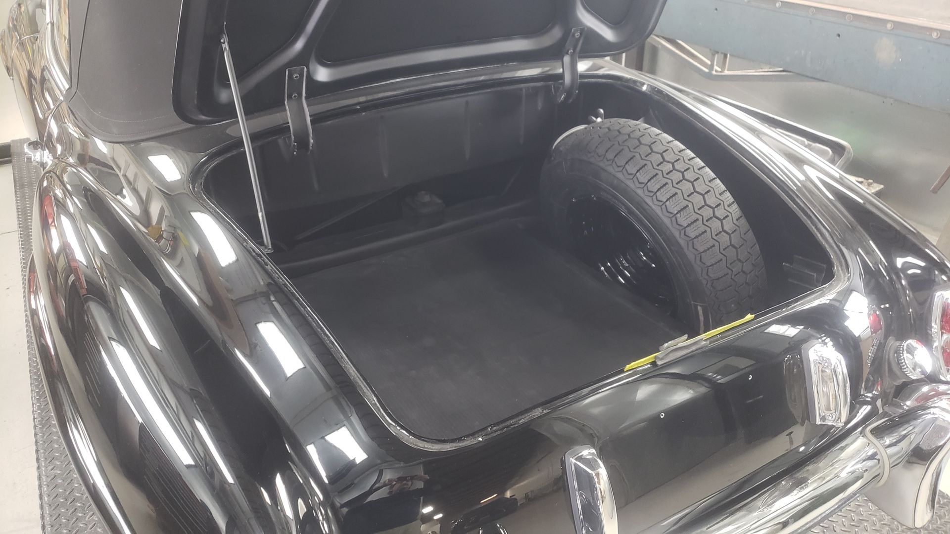 Black car trunk with a spare tire, open.