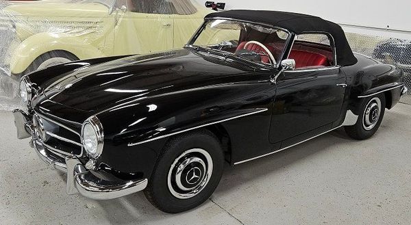 Black Mercedes-Benz 190SL convertible with a red interior and black soft top.