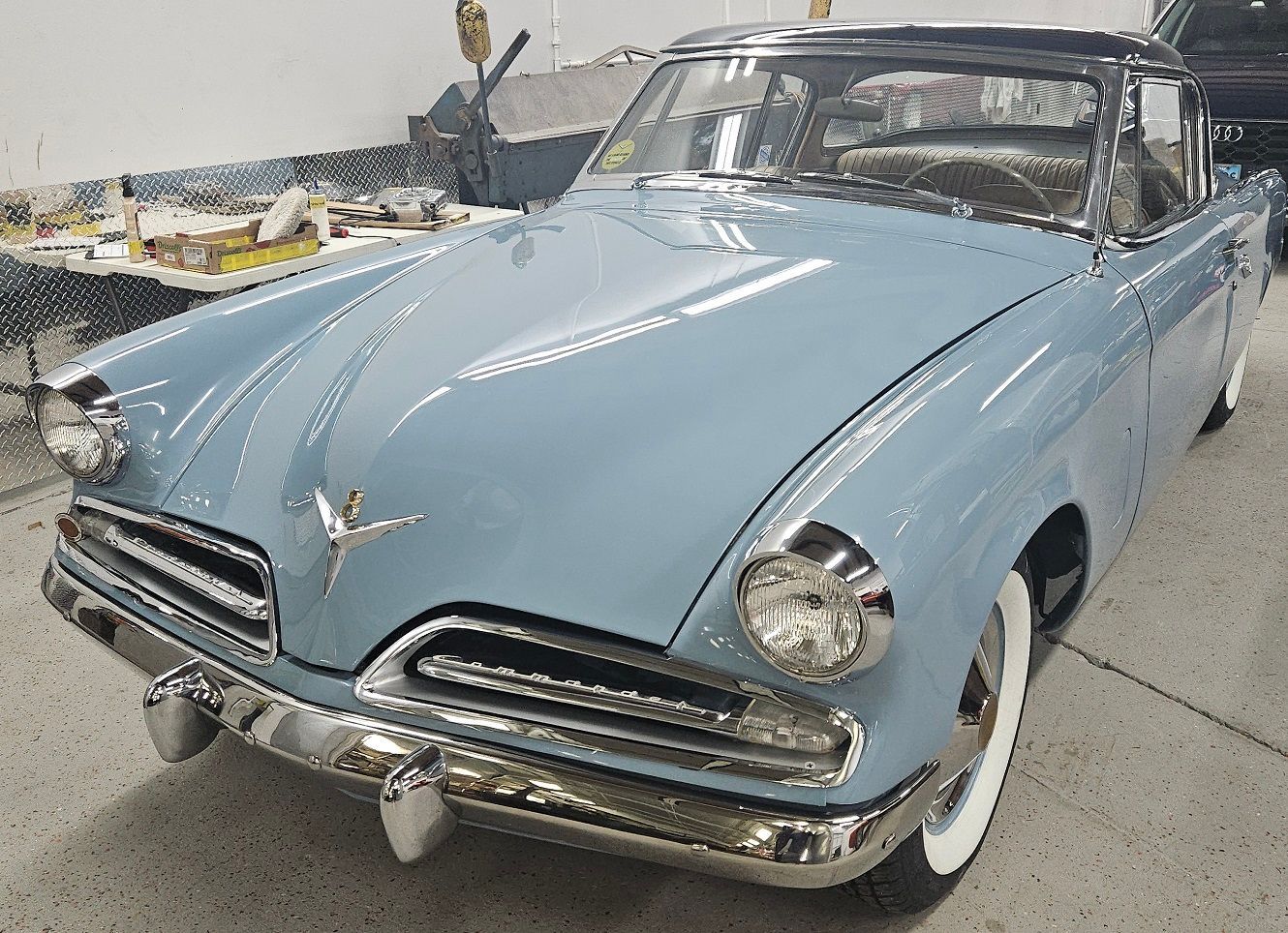 Blue and black vintage Studebaker car with chrome accents and whitewall tires.
