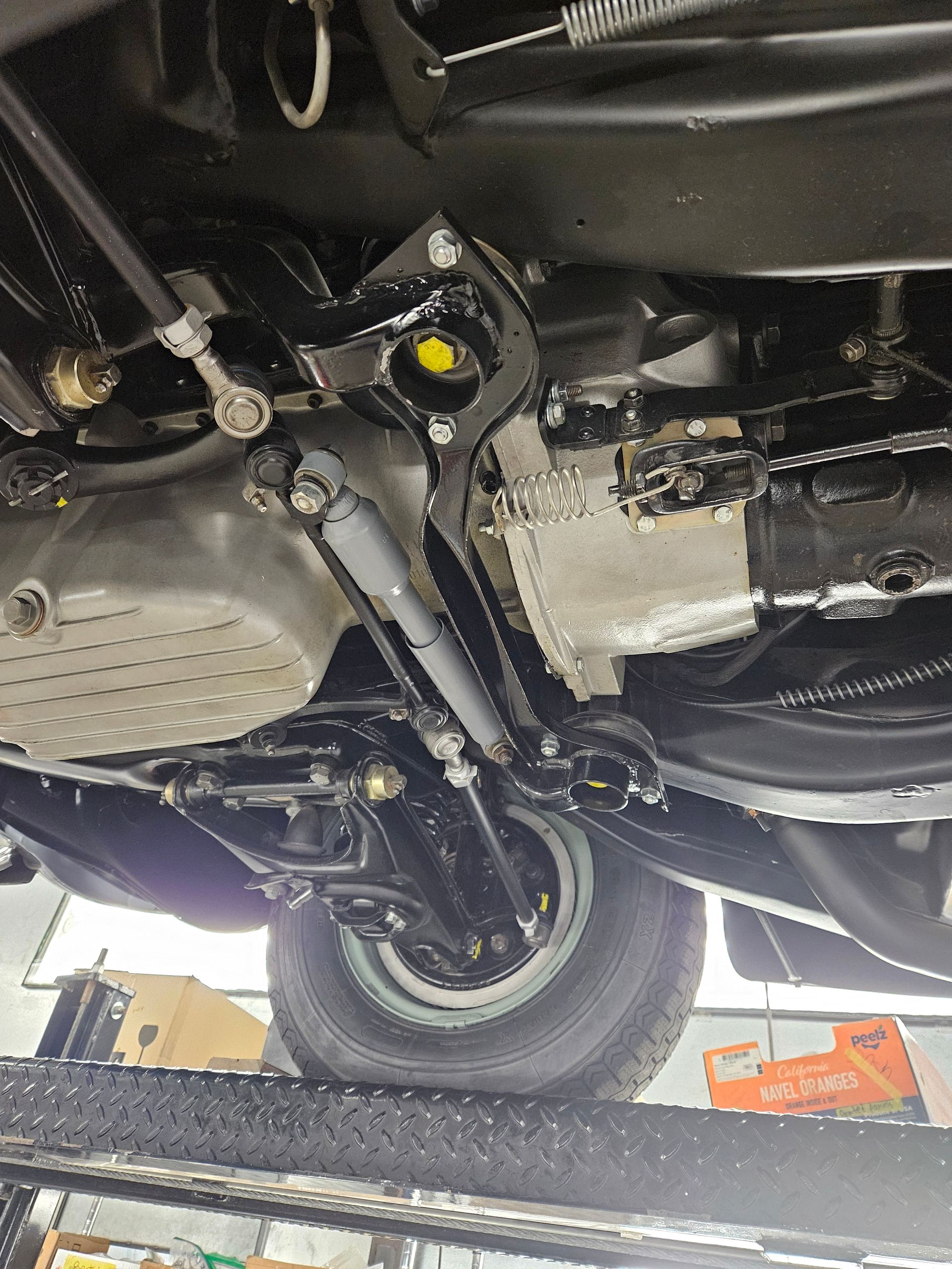 Undercarriage of a black vintage car, with a wheel, suspension, and engine components visible.
