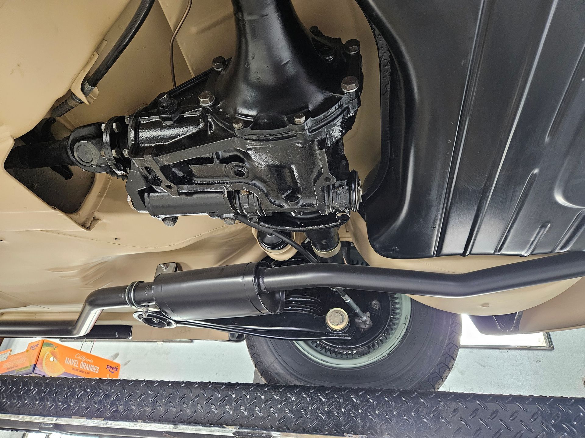 Underside view of a black-painted car chassis, including the differential, driveshaft, and exhaust system