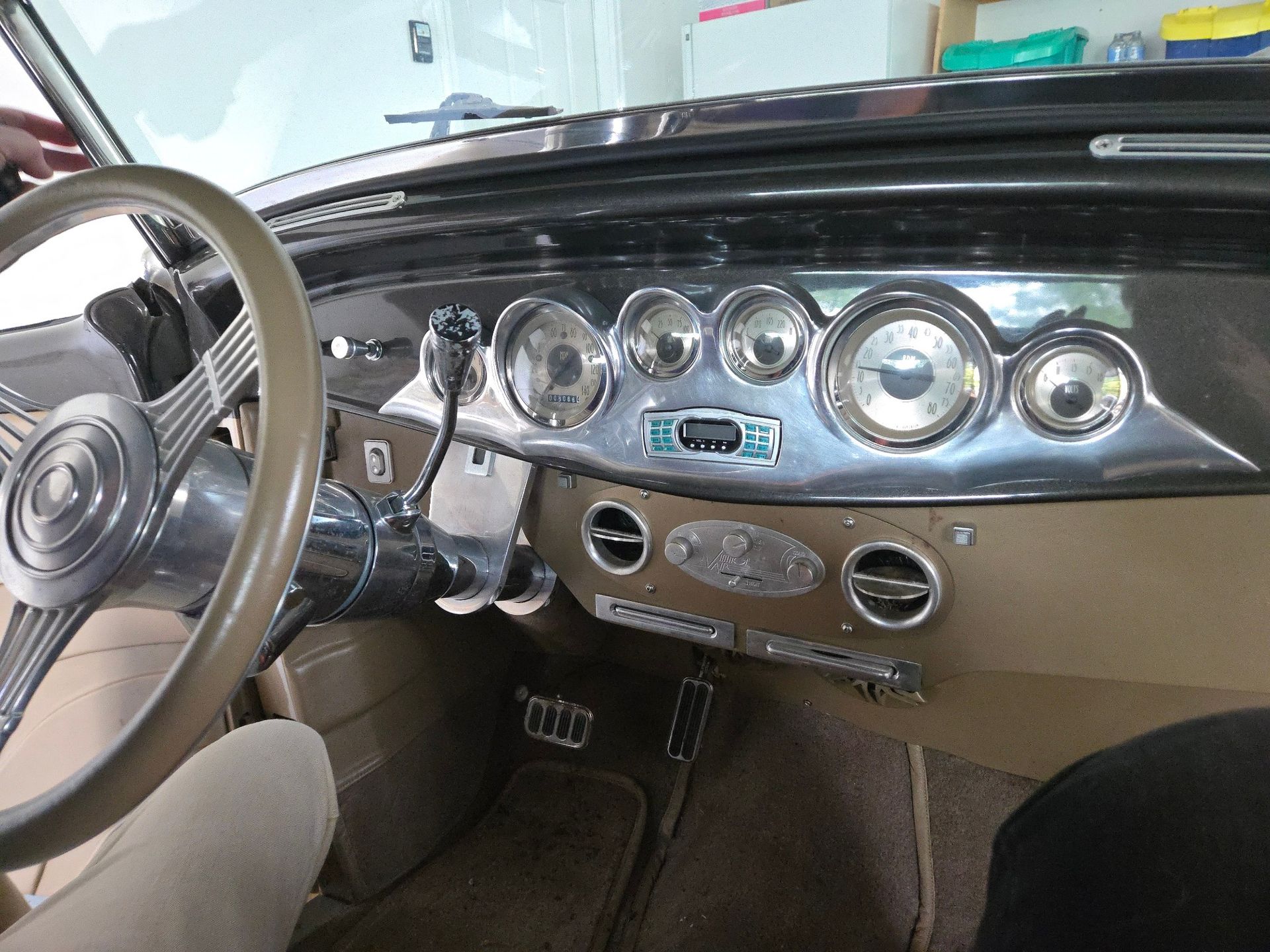 Interior of a vintage car with beige and silver dashboard, steering wheel, and gauges.
