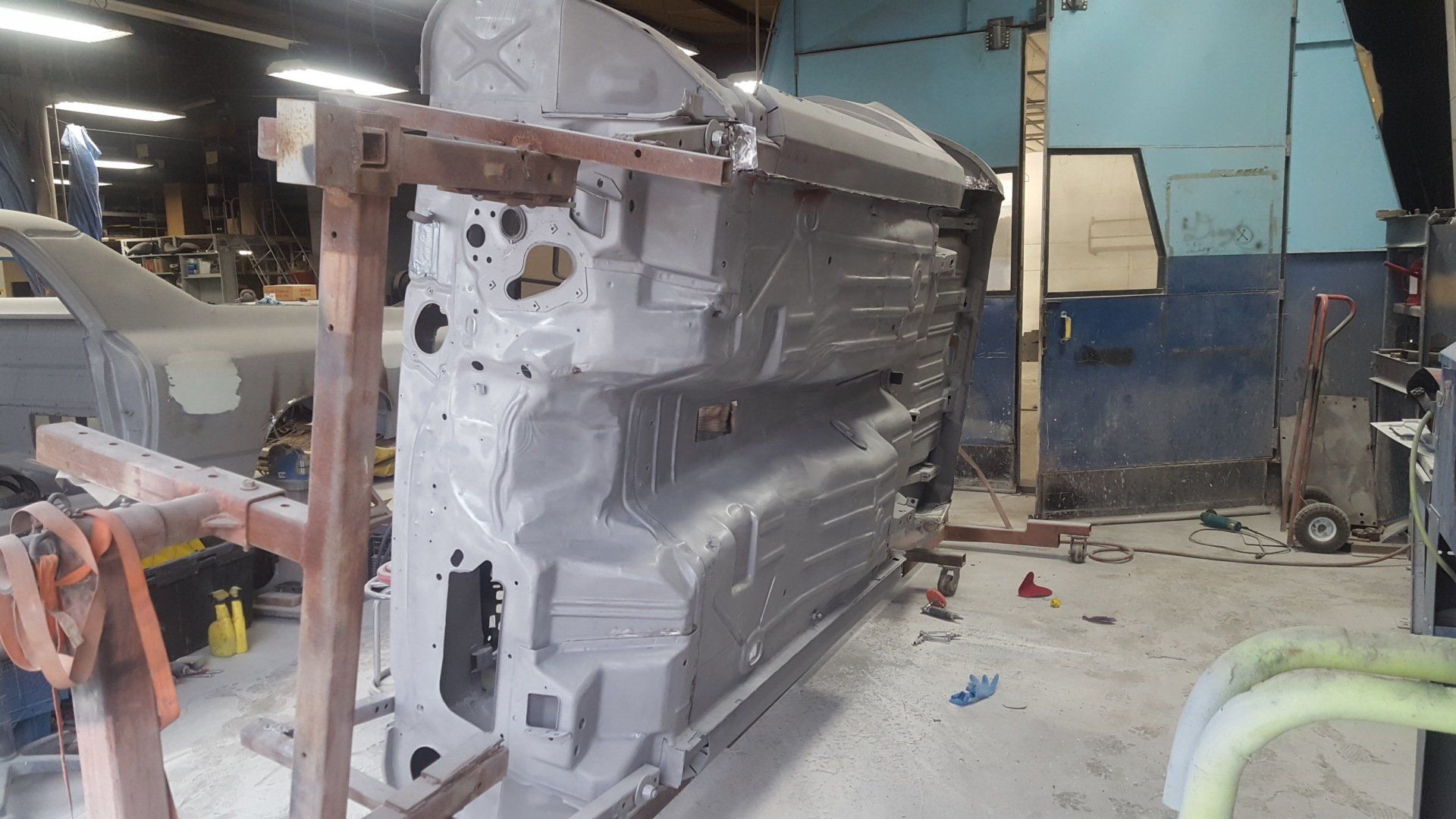 Car frame, gray, upside down, on a metal support, in a repair shop.