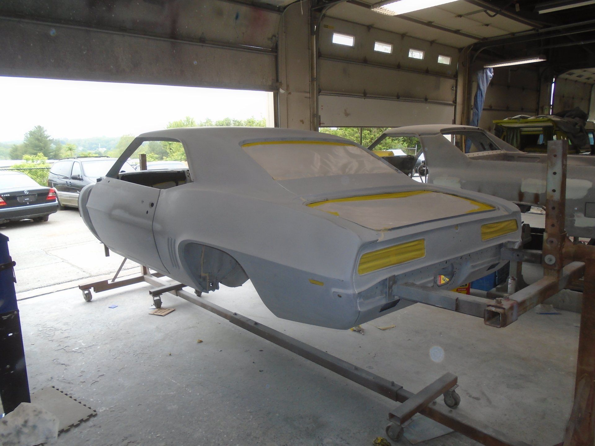 A classic gray car body in a workshop, raised on a frame for restoration work.