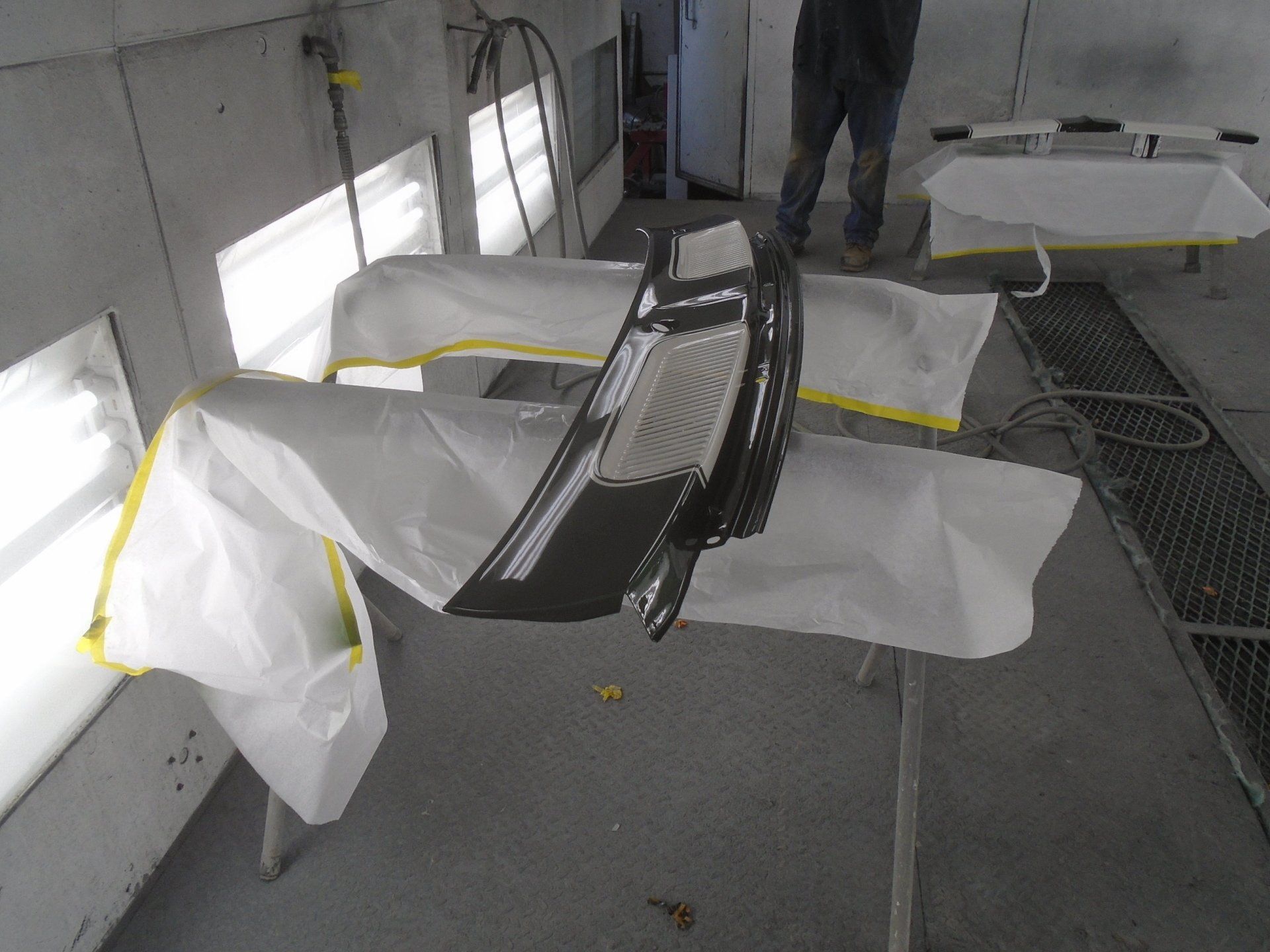 Car bumper being painted inside a spray booth.