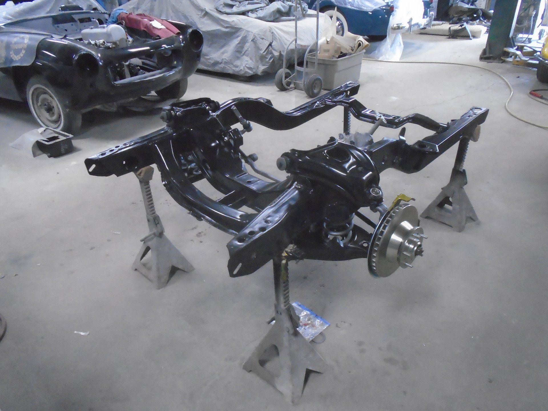 Black car chassis on jack stands in a garage.