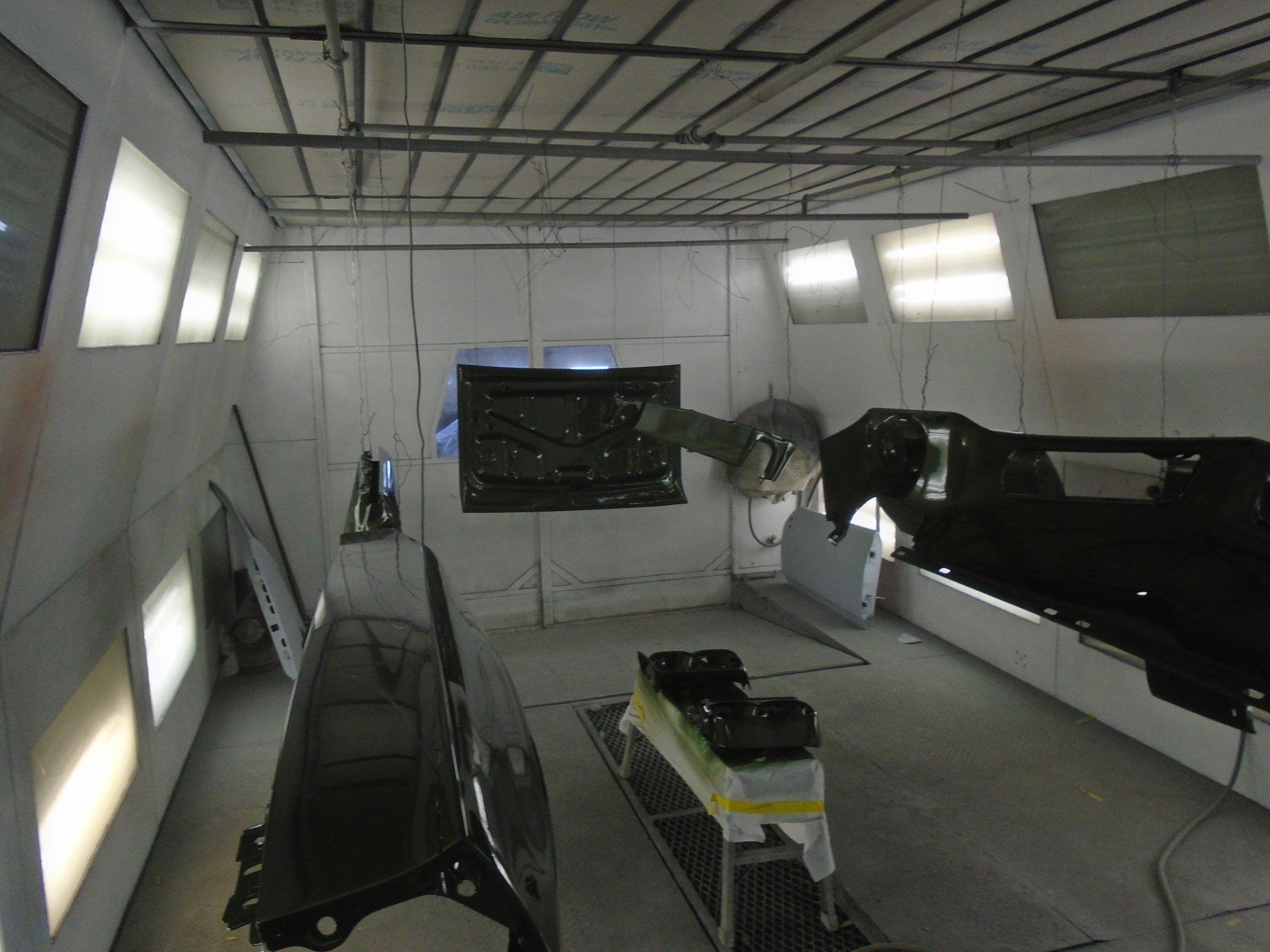 Spray paint booth with car parts, bright lights.