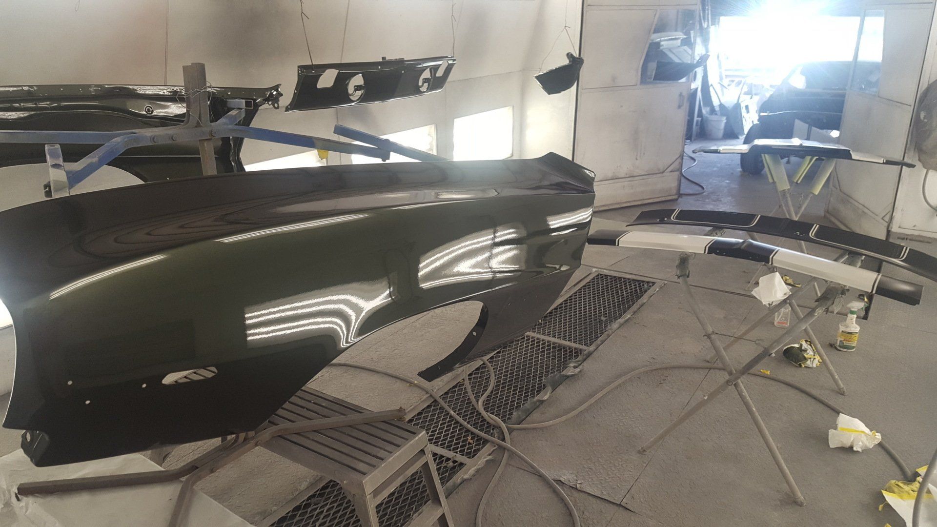 Car parts in a spray booth, painted green, awaiting final assembly.