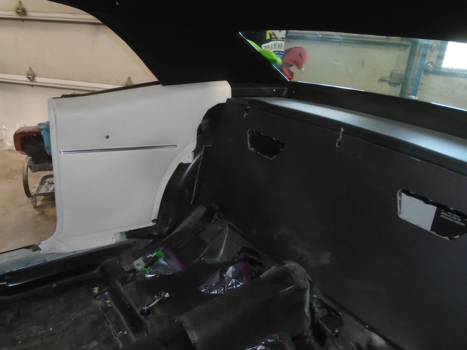 Interior of a classic car being restored; white panels, dark grey firewall, black interior components.