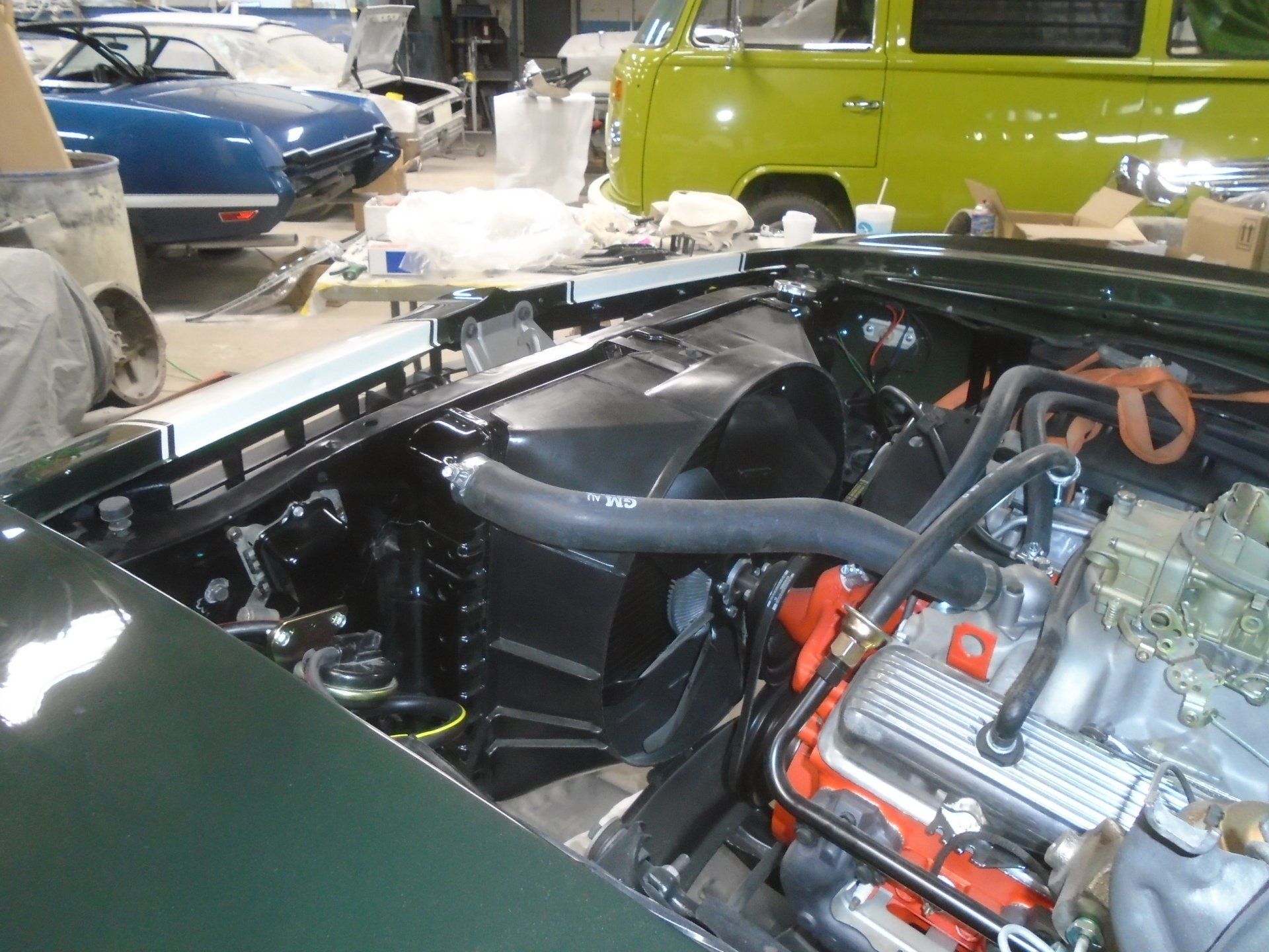 Green car engine bay with black components, gray hose, and silver engine details.