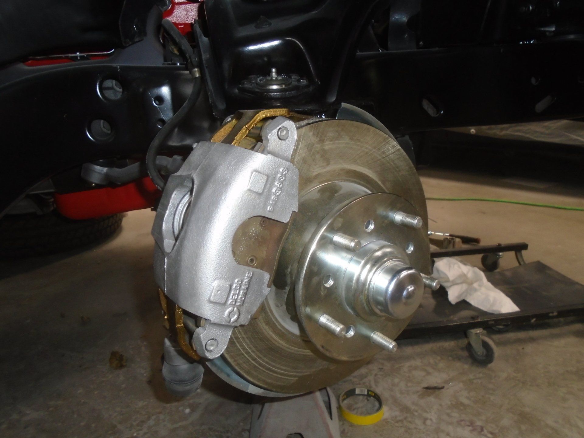Silver disc brake assembly on a black car chassis, ready for installation.