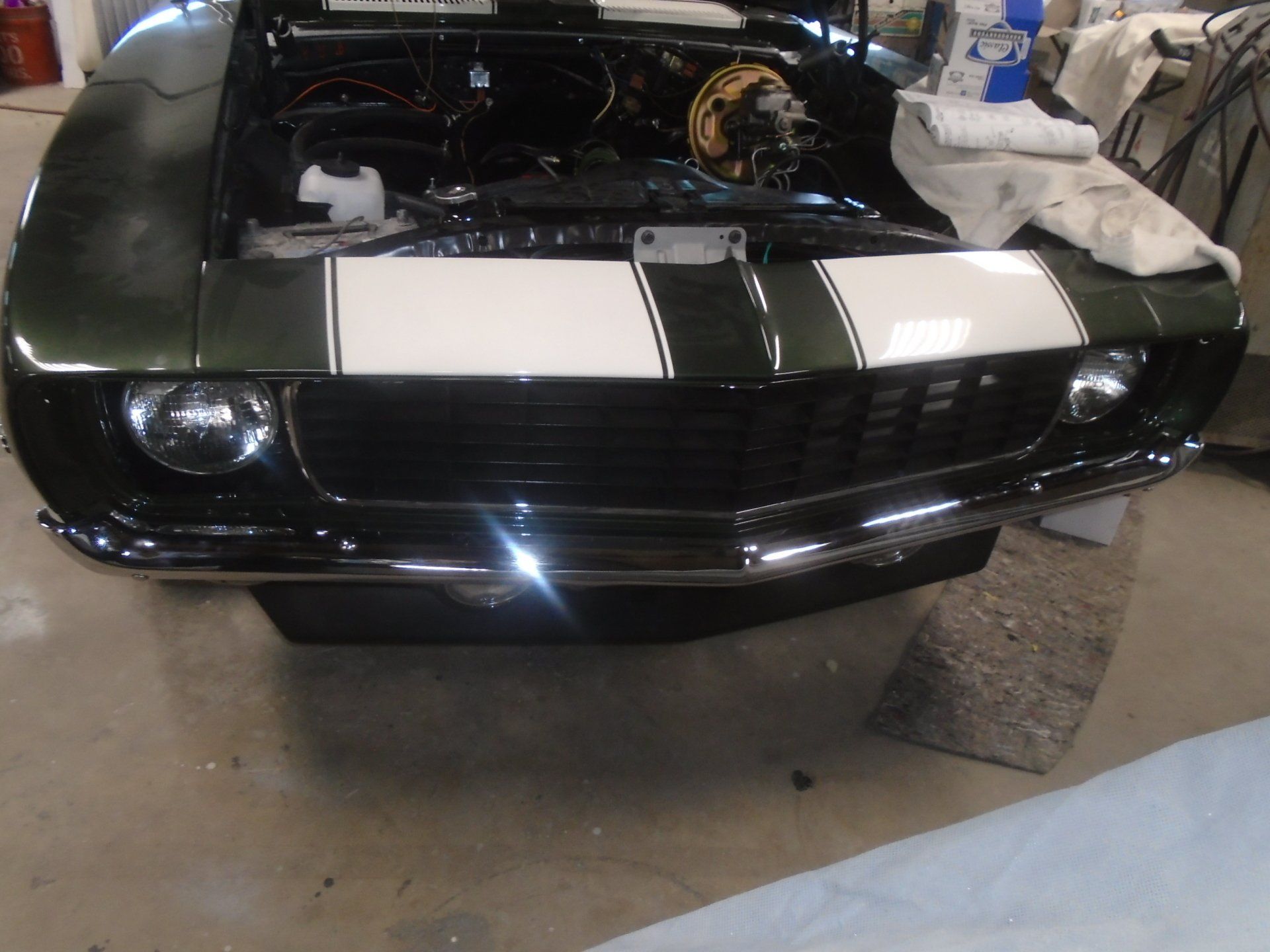 Green classic car front with white stripes and chrome trim.