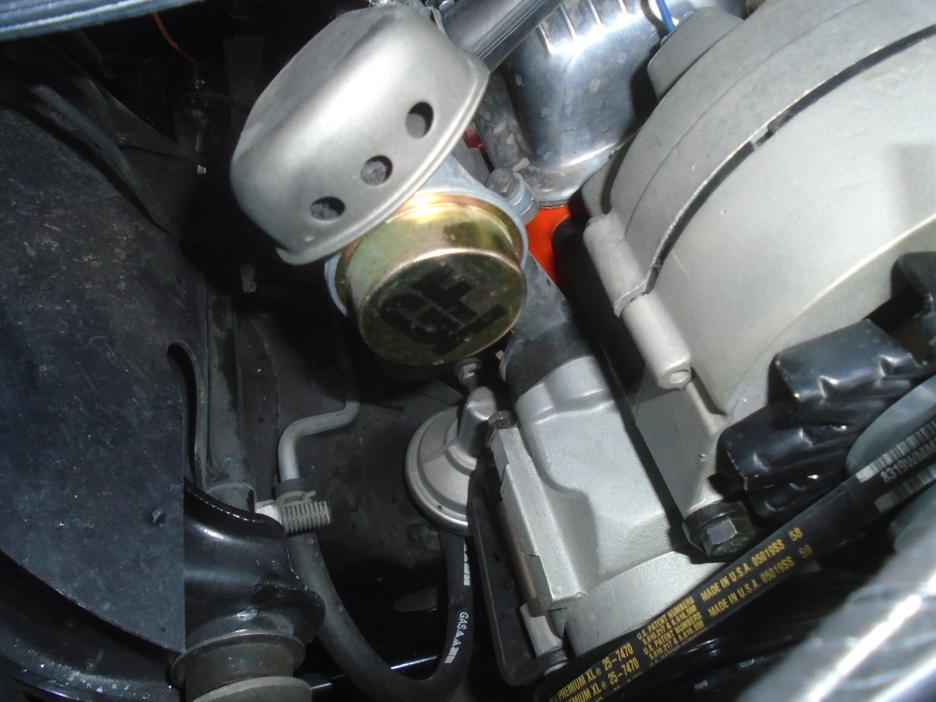 Engine components: carburetor, alternator, and fuel pump, in an engine bay.