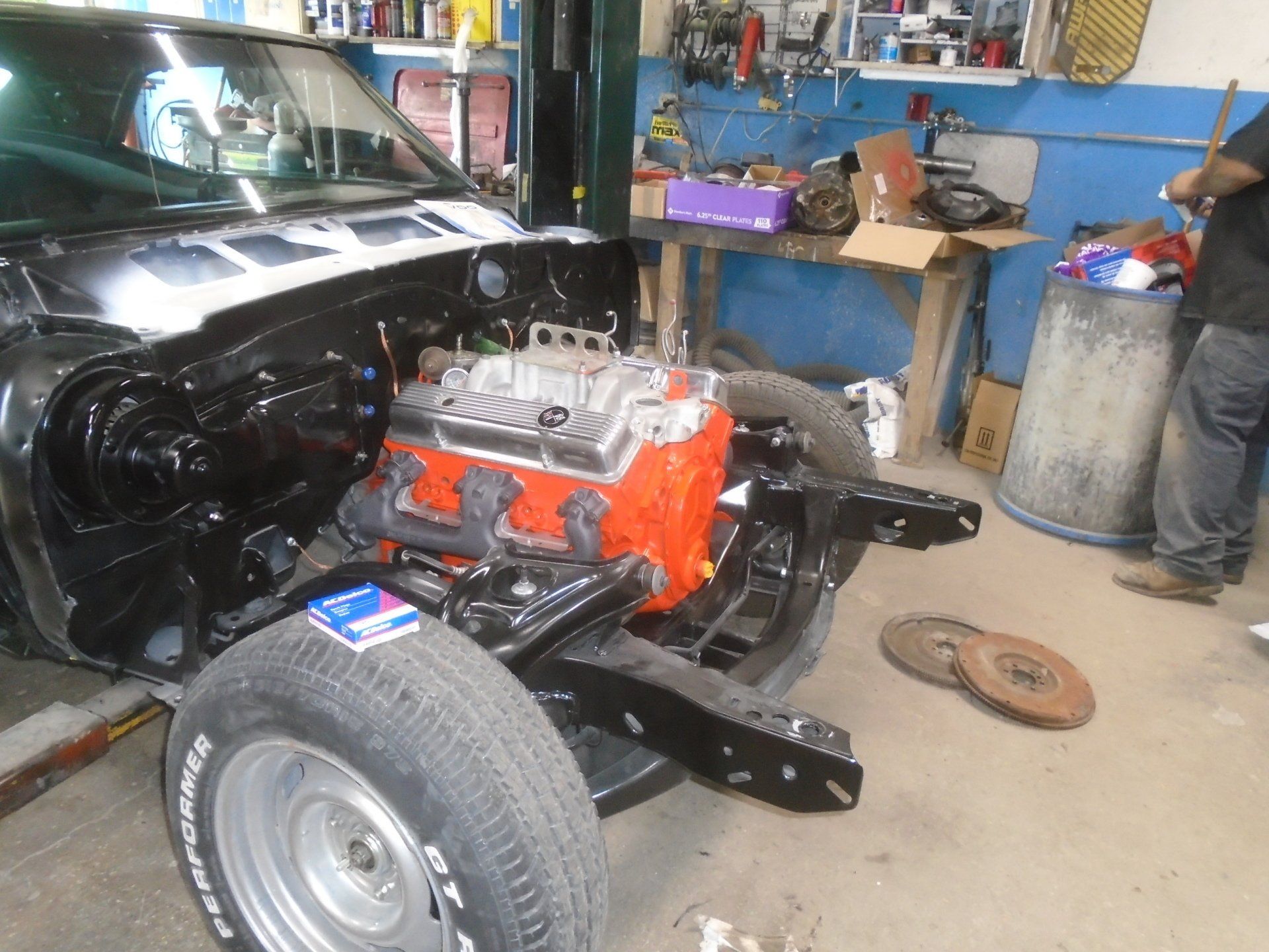 Black car frame with orange engine in a garage.