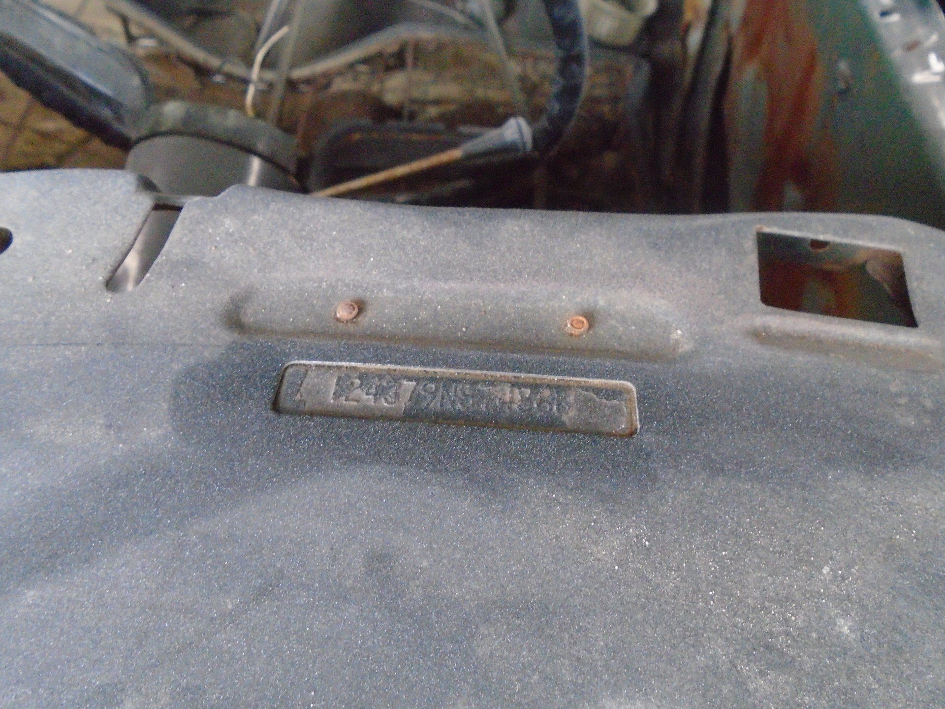Dashboard of a vintage car with a metal VIN plate and rusty fasteners.