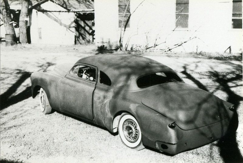 Customized vintage car with smoothed body, low profile, and whitewall tires parked outdoors.