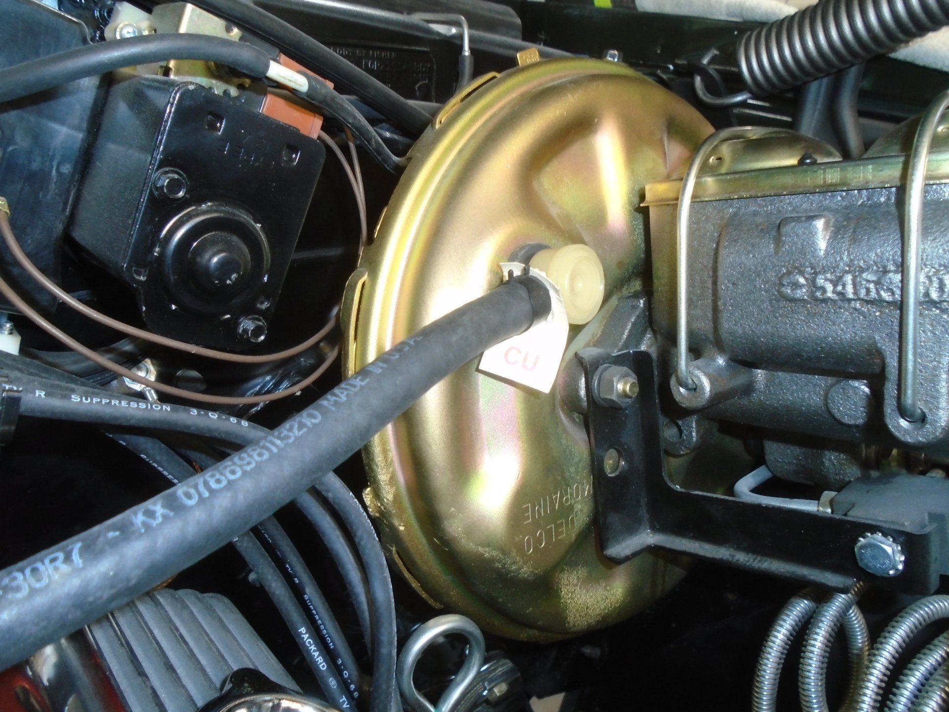 Close-up of a car's brake booster system, including the vacuum hose, master cylinder, and brake booster.