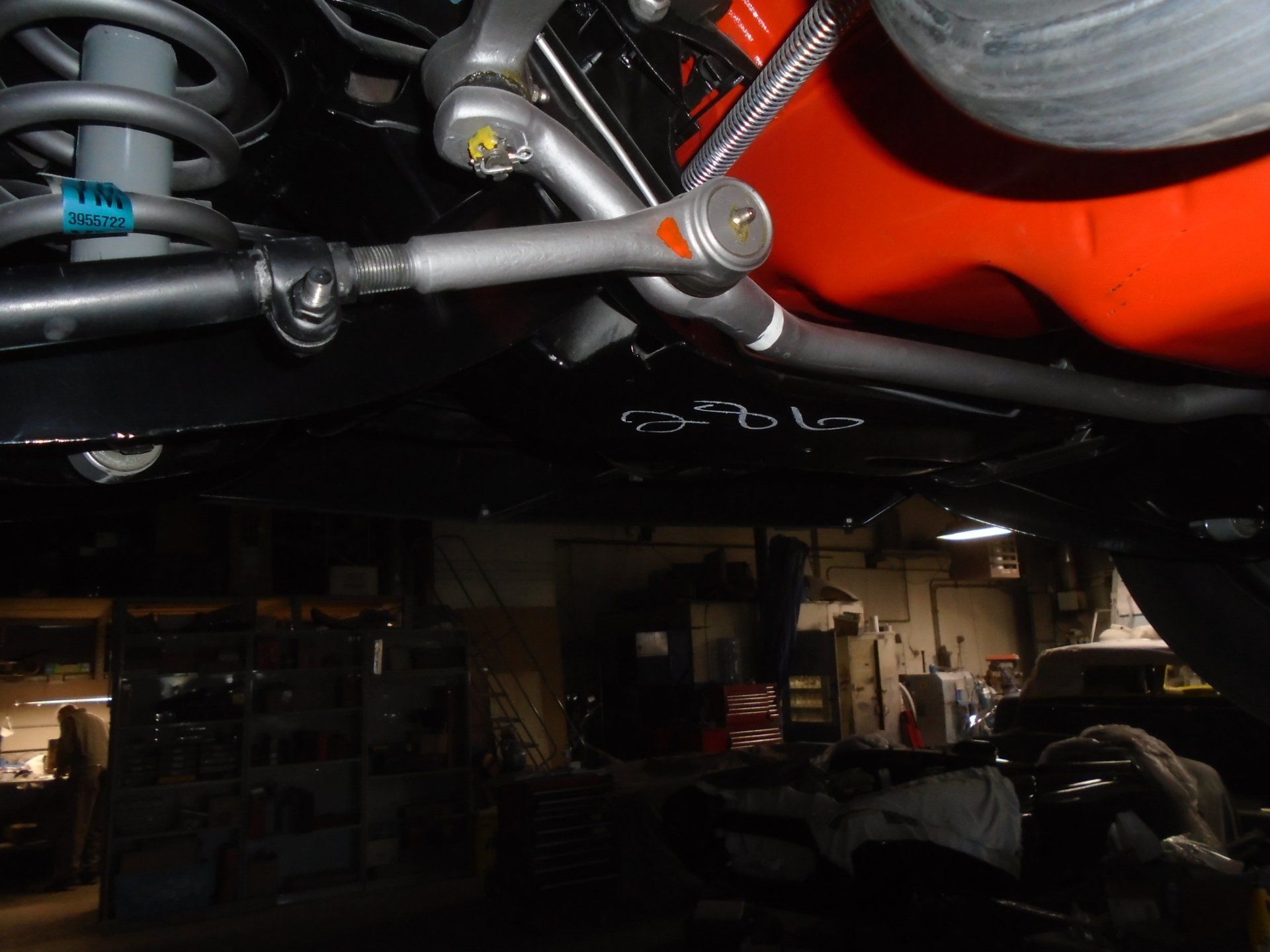 Undercarriage of a classic car, showing steering components, suspension, and orange engine block.