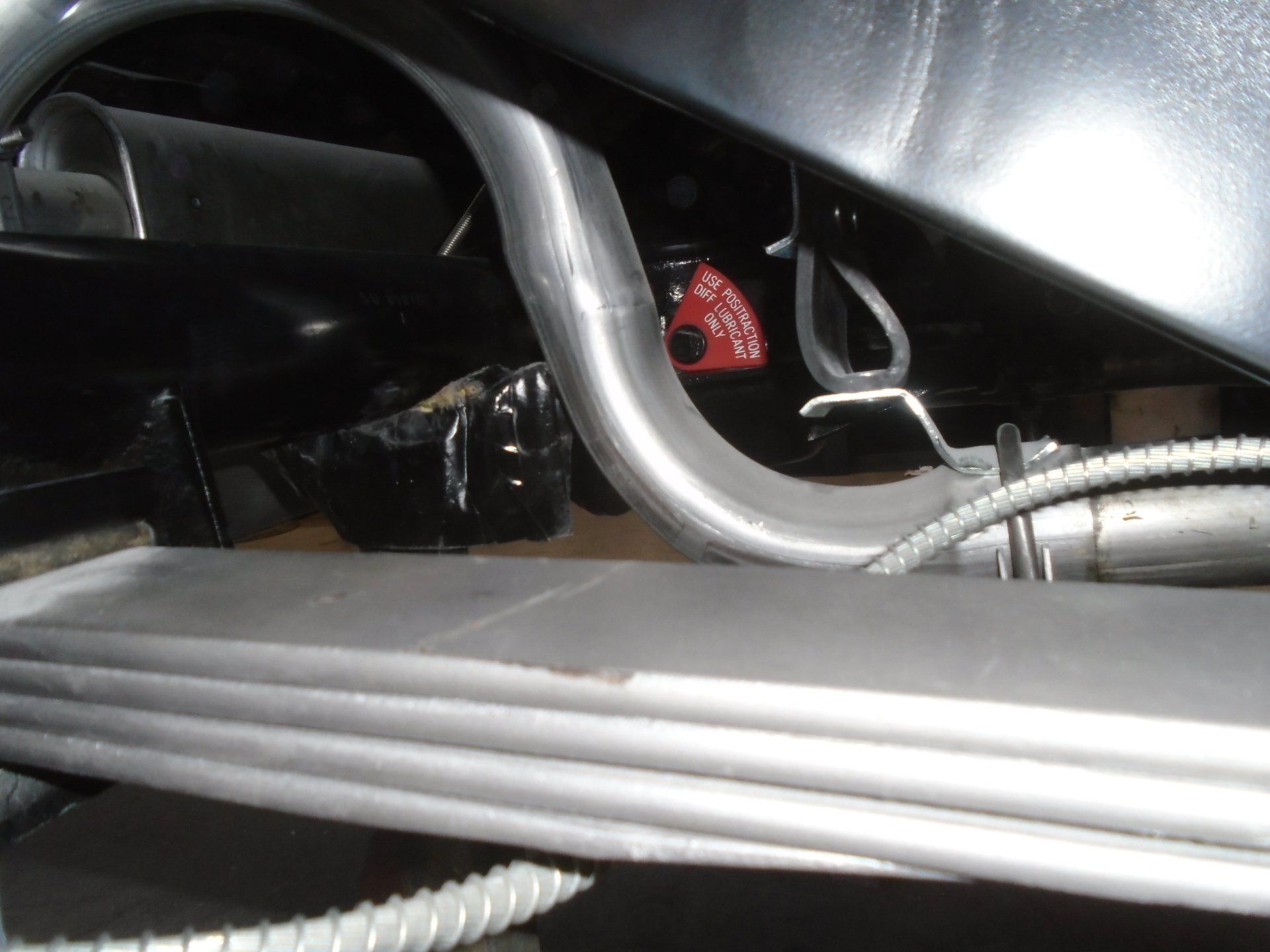 Exhaust pipe routing near a black vehicle chassis, a red component visible.