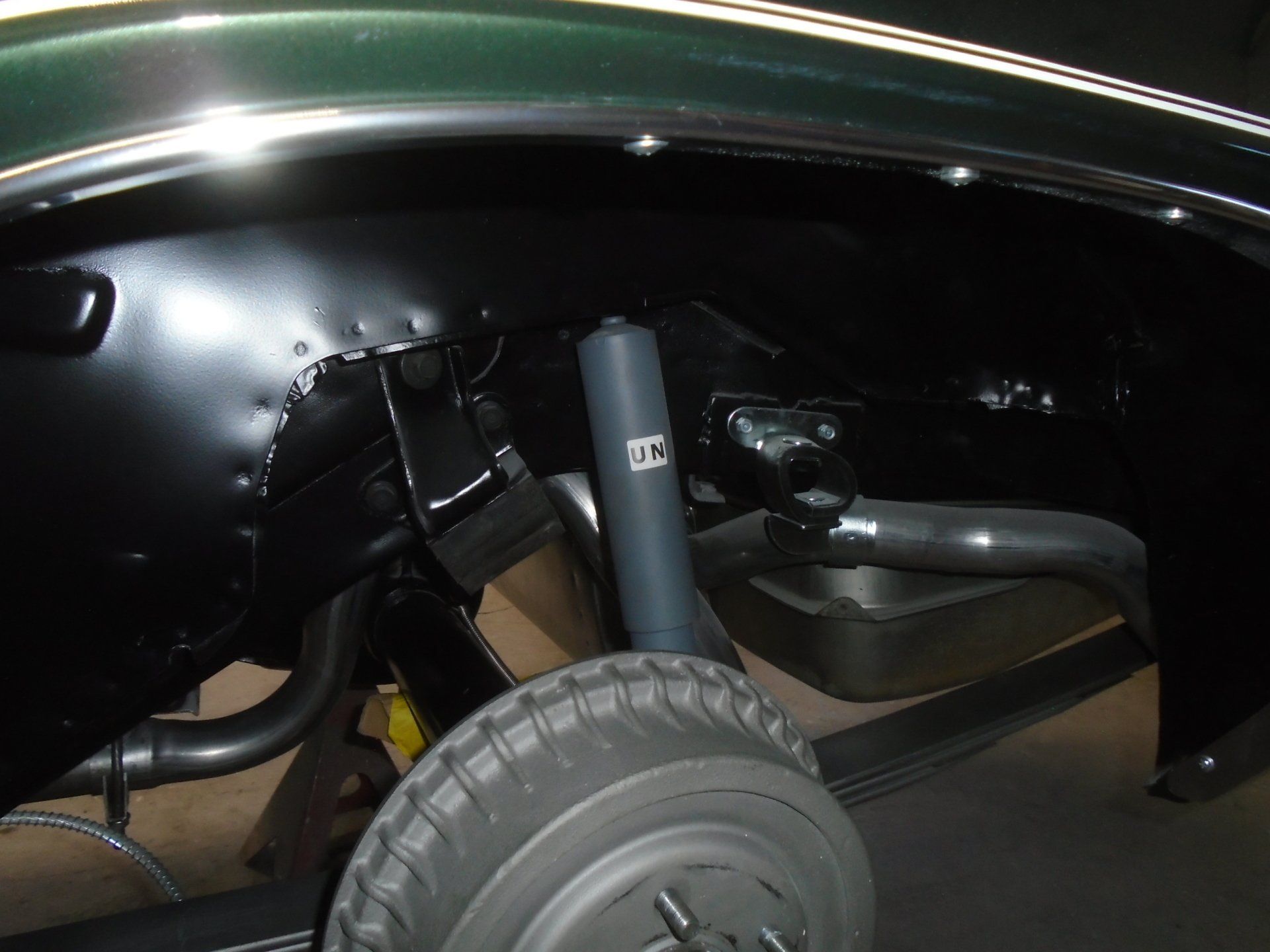 Black car undercarriage with shock absorber, tire, and suspension components visible.