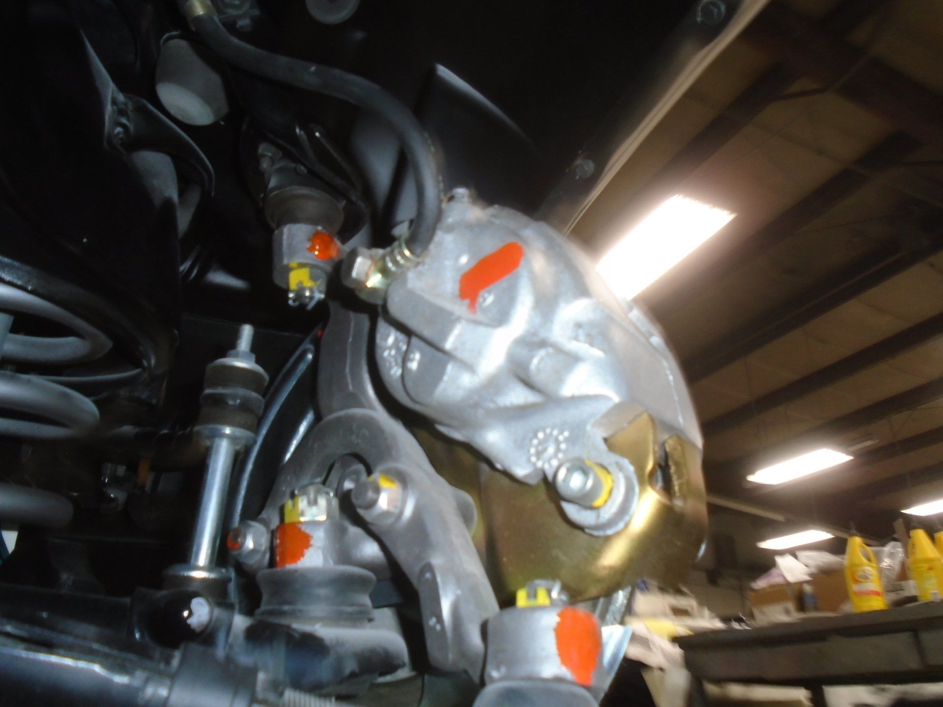 Car brake caliper assembly with gold and silver components, with orange protective caps.