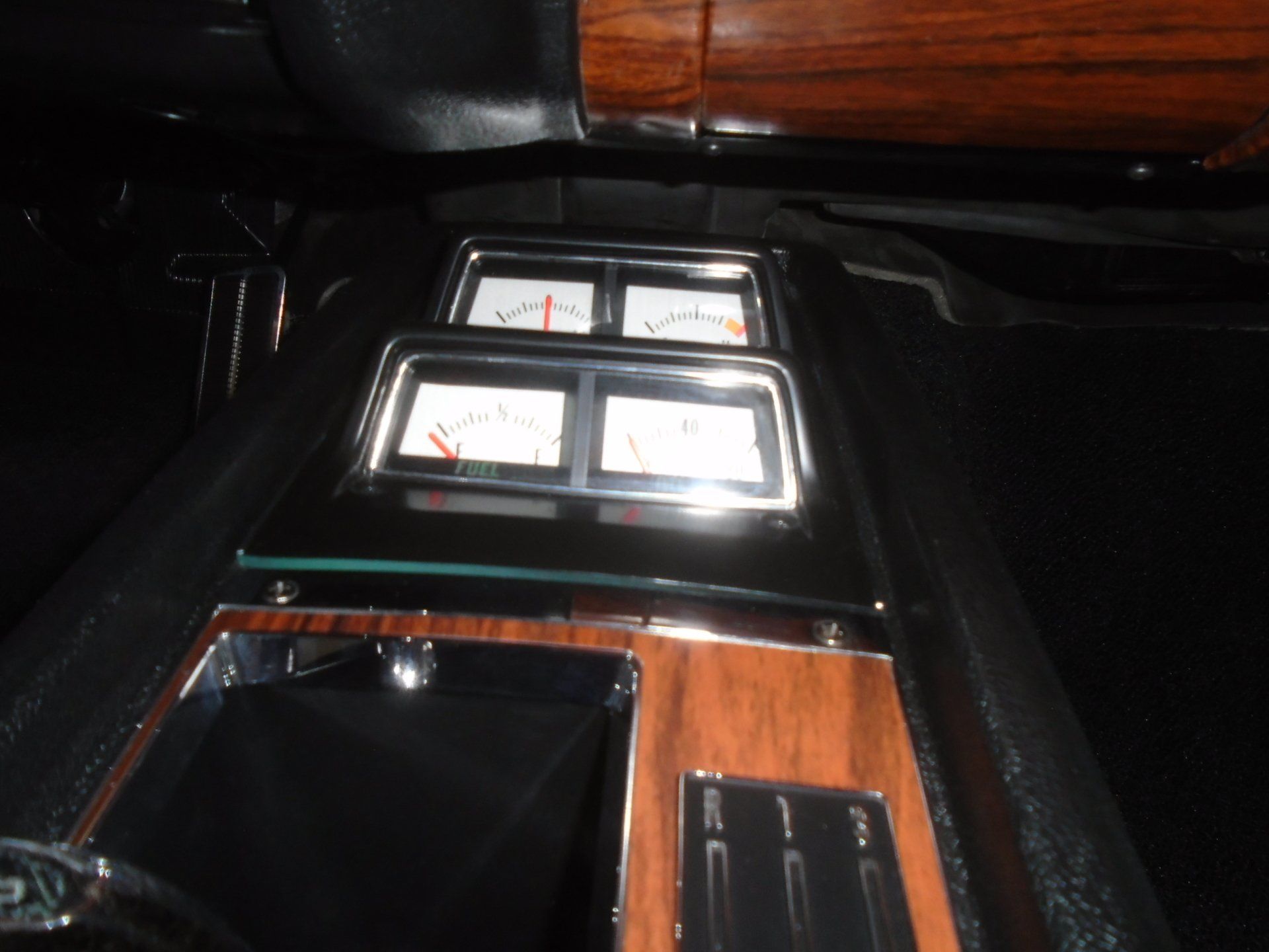 Car interior with wood trim and gauges, including a volt meter and fuel gauge.