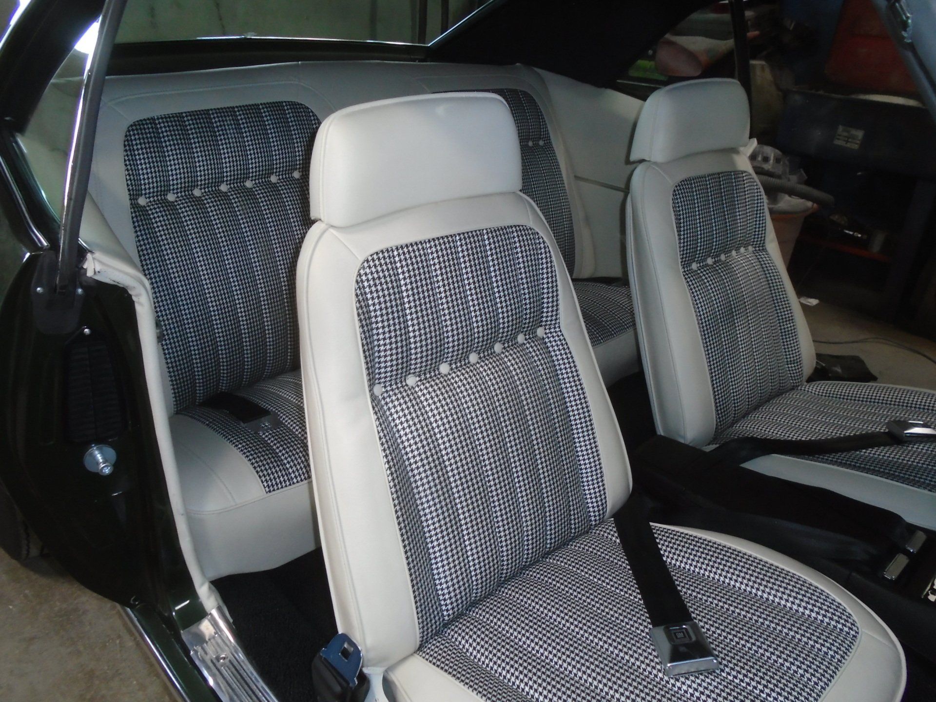 Black classic car interior with patterned gray and white seats.