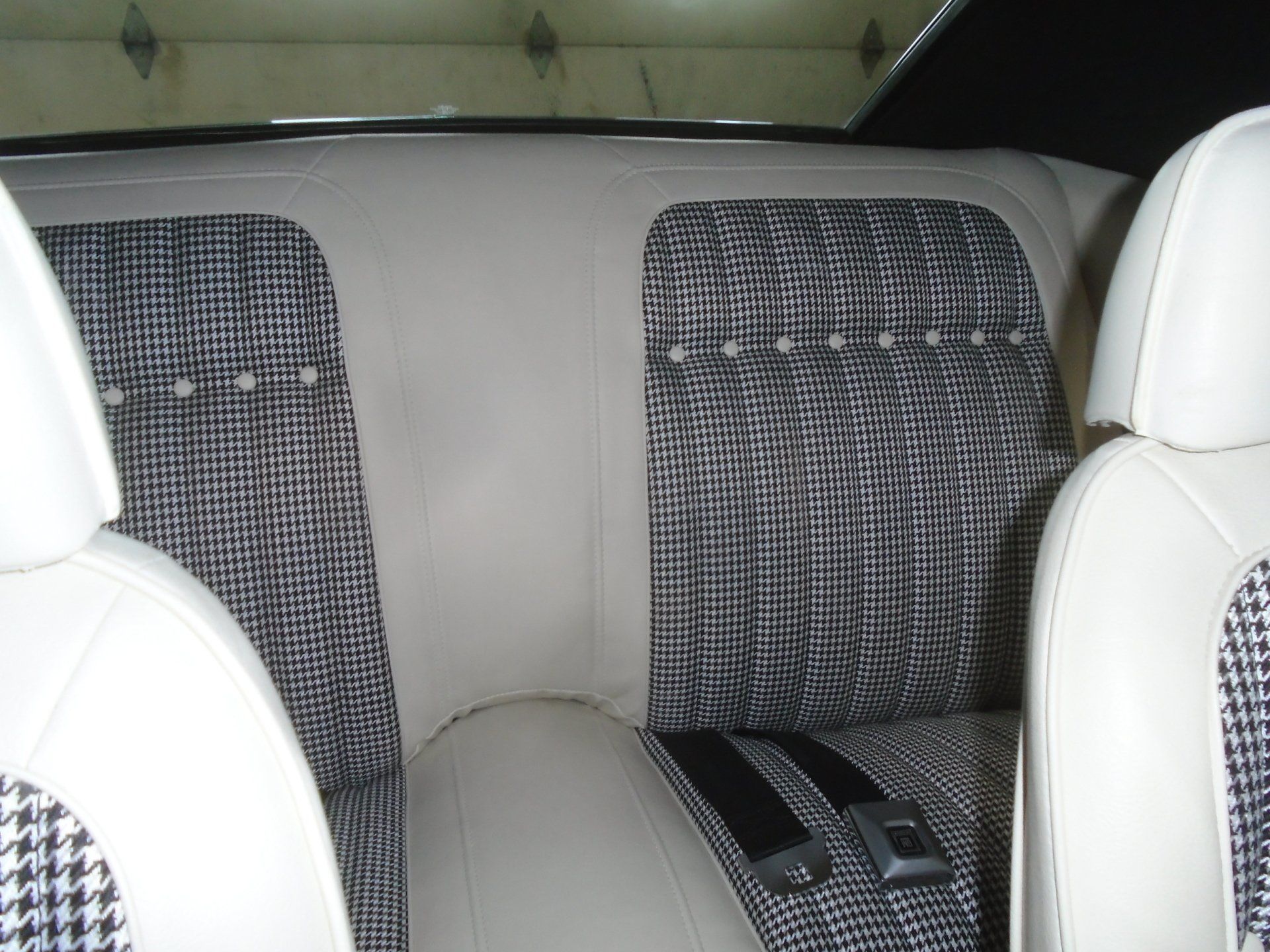 Classic car interior, white leather seats with black and white patterned inserts and a matching back seat.