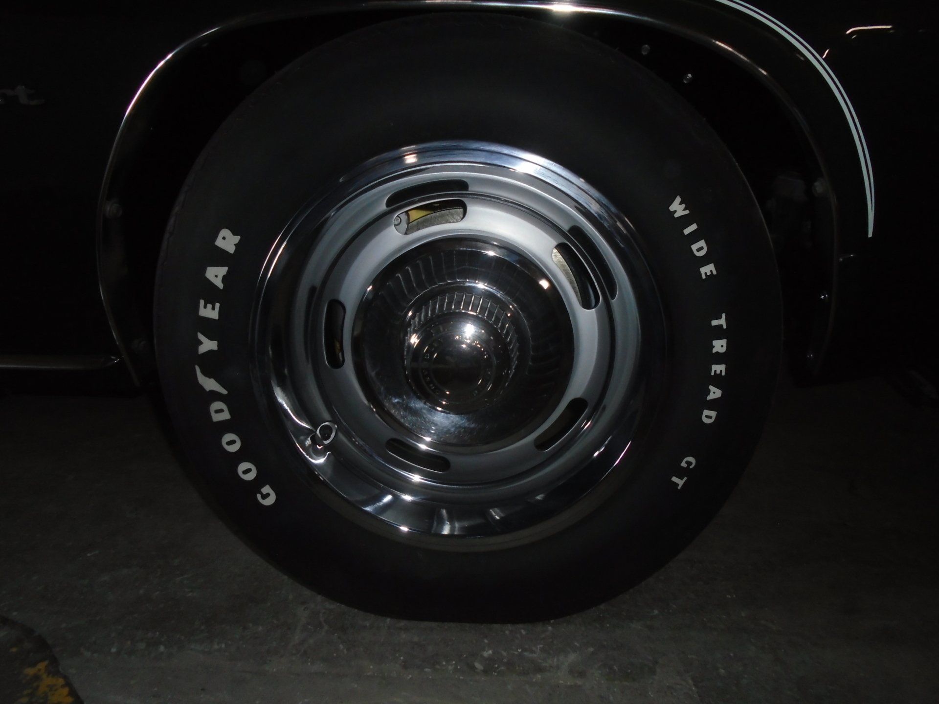 Black car tire with chrome hubcap; white 