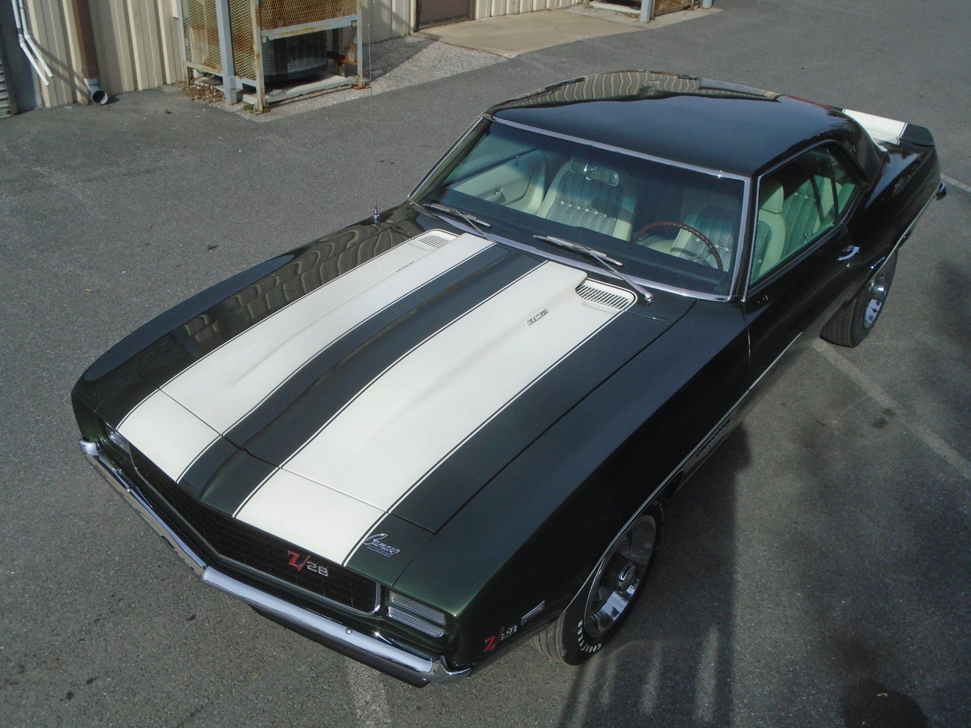 Black and white 1969 Chevy Camaro Z/28 with white racing stripes, parked on asphalt.