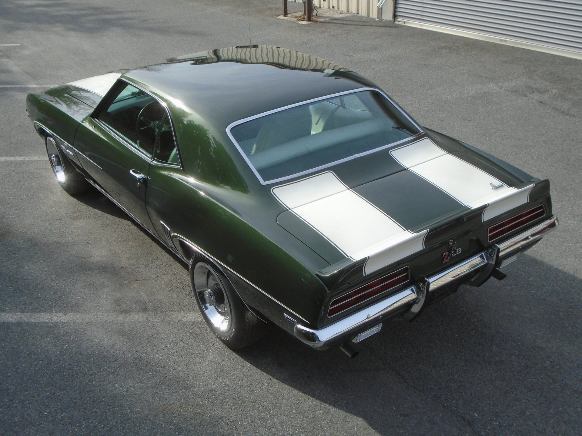 Green and white striped classic car parked on asphalt.