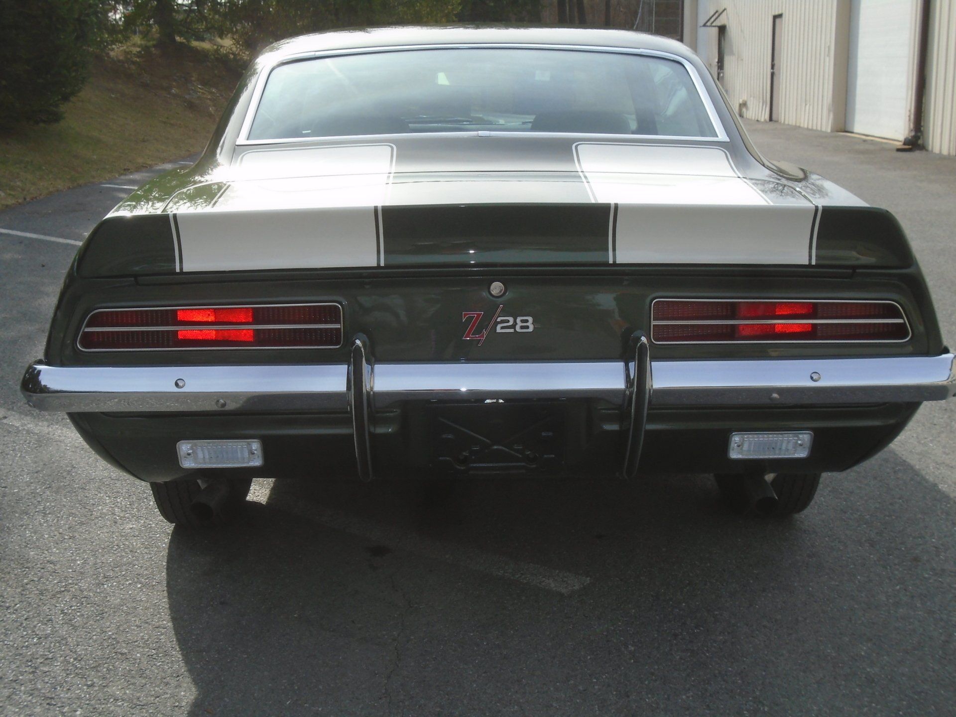 Rear view of a dark green 1969 Chevrolet Camaro Z/28 with white racing stripes.
