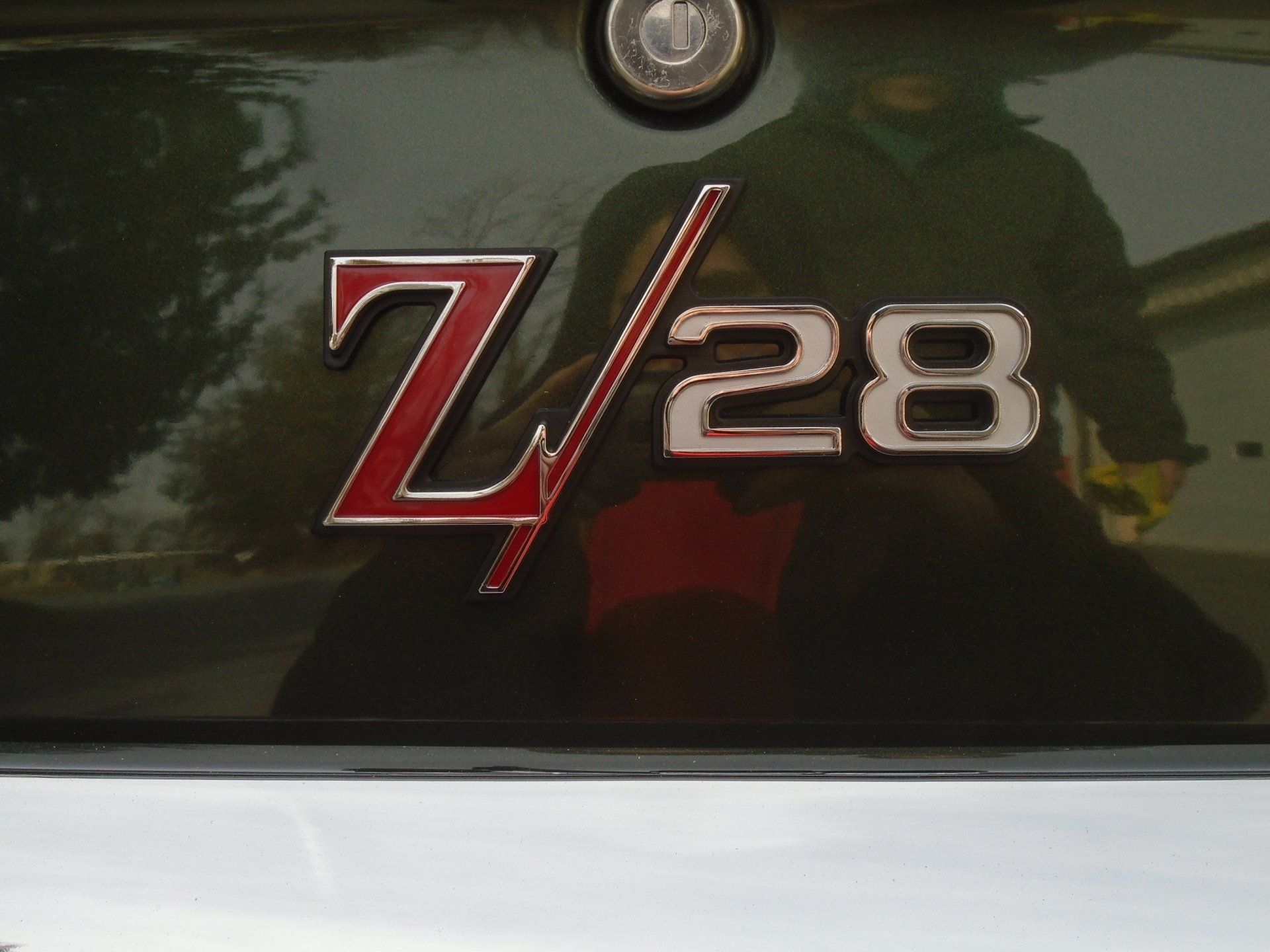 Close-up of a dark green car trunk with a red and silver Z/28 emblem.