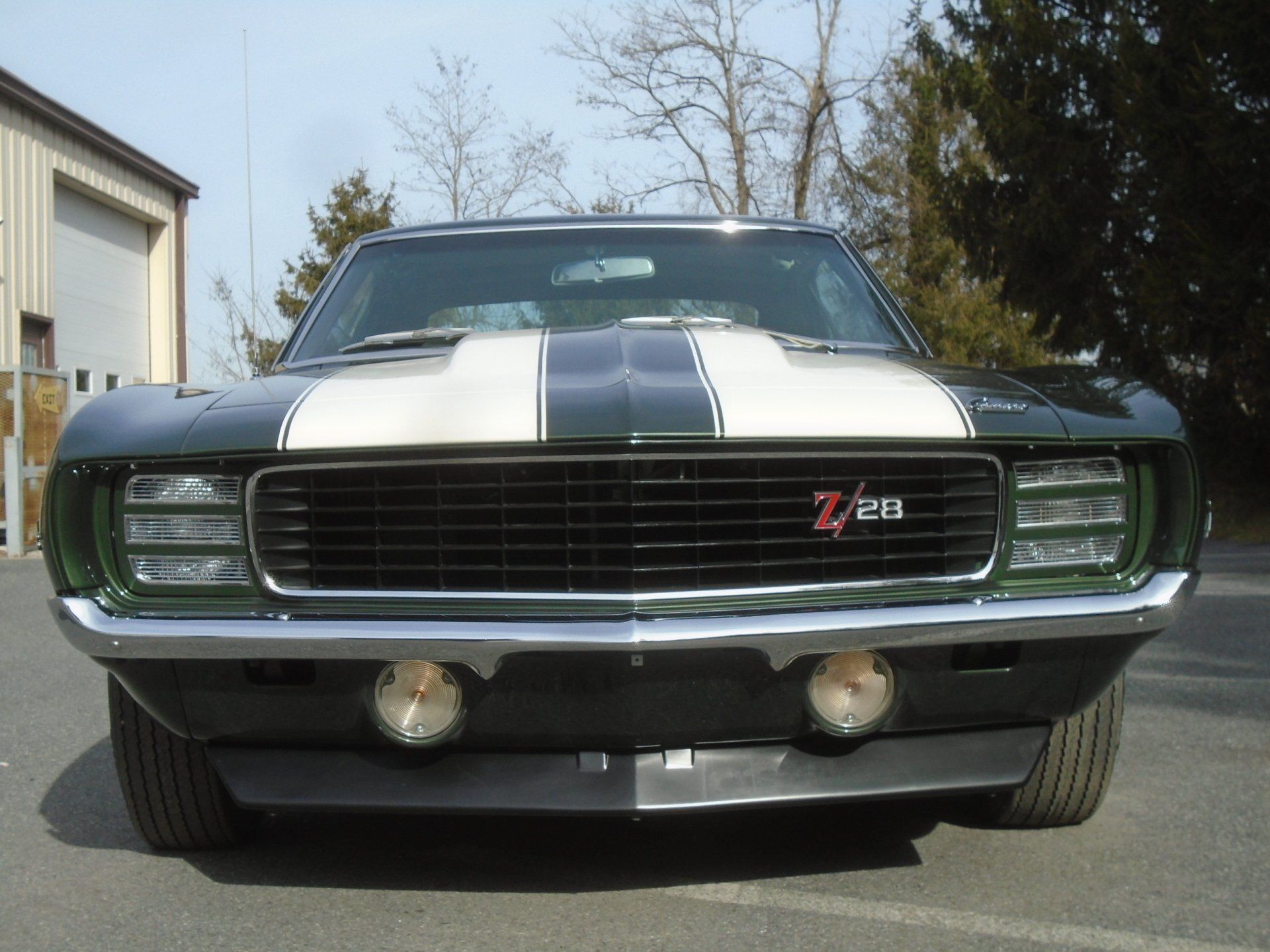 Dark green 1969 Chevrolet Camaro Z/28 with white stripes, black grill, and fog lights.