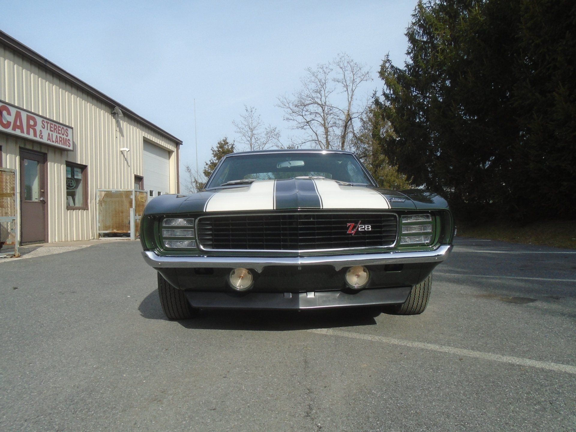 Green and white 1969 Chevrolet Camaro Z/28 muscle car parked in front of a building.