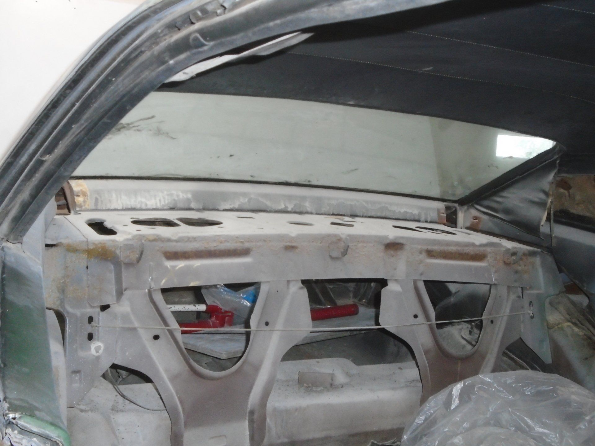Interior car view with a removed rear window, showing bare metal framework.