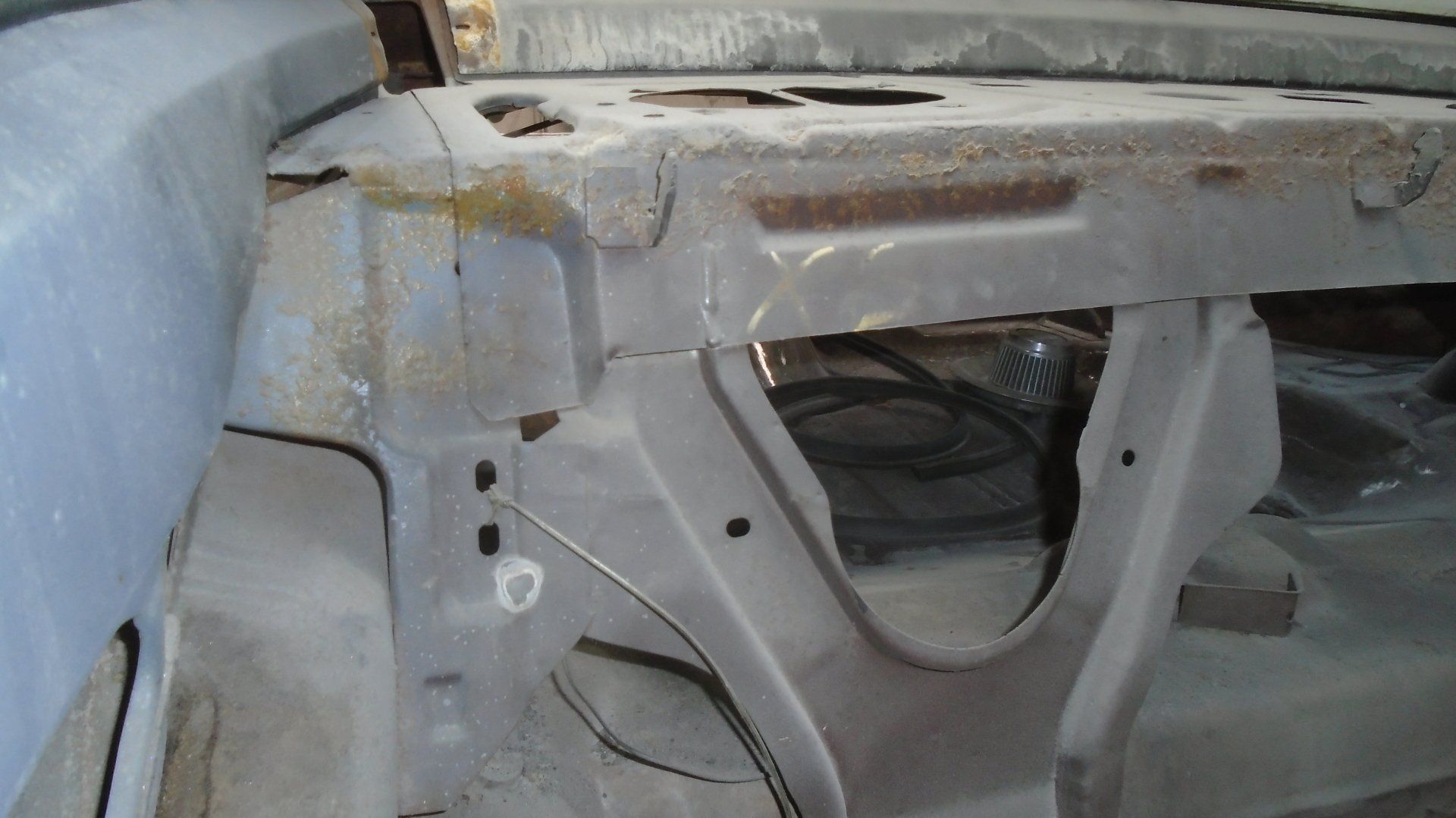 Interior car frame undergoing restoration, showing rusted metal and various structural components.