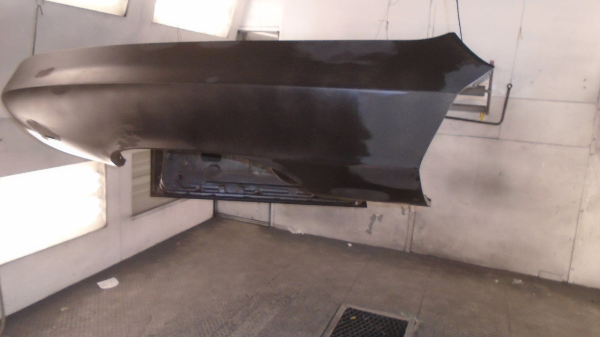 Black car panel in a paint booth.